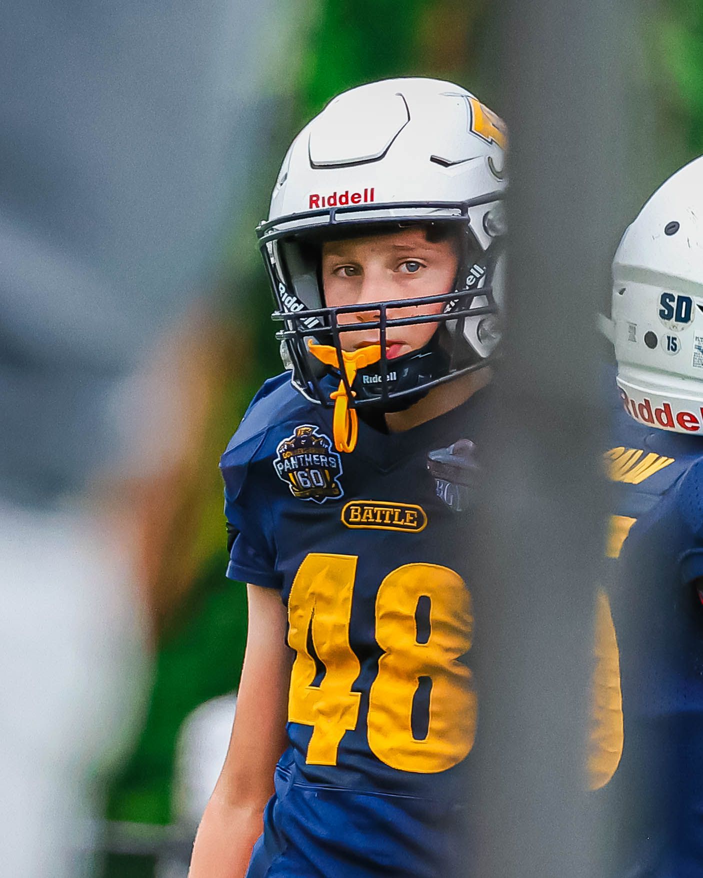 Youth football player wearing blue uniform with number 48 and white helmet.