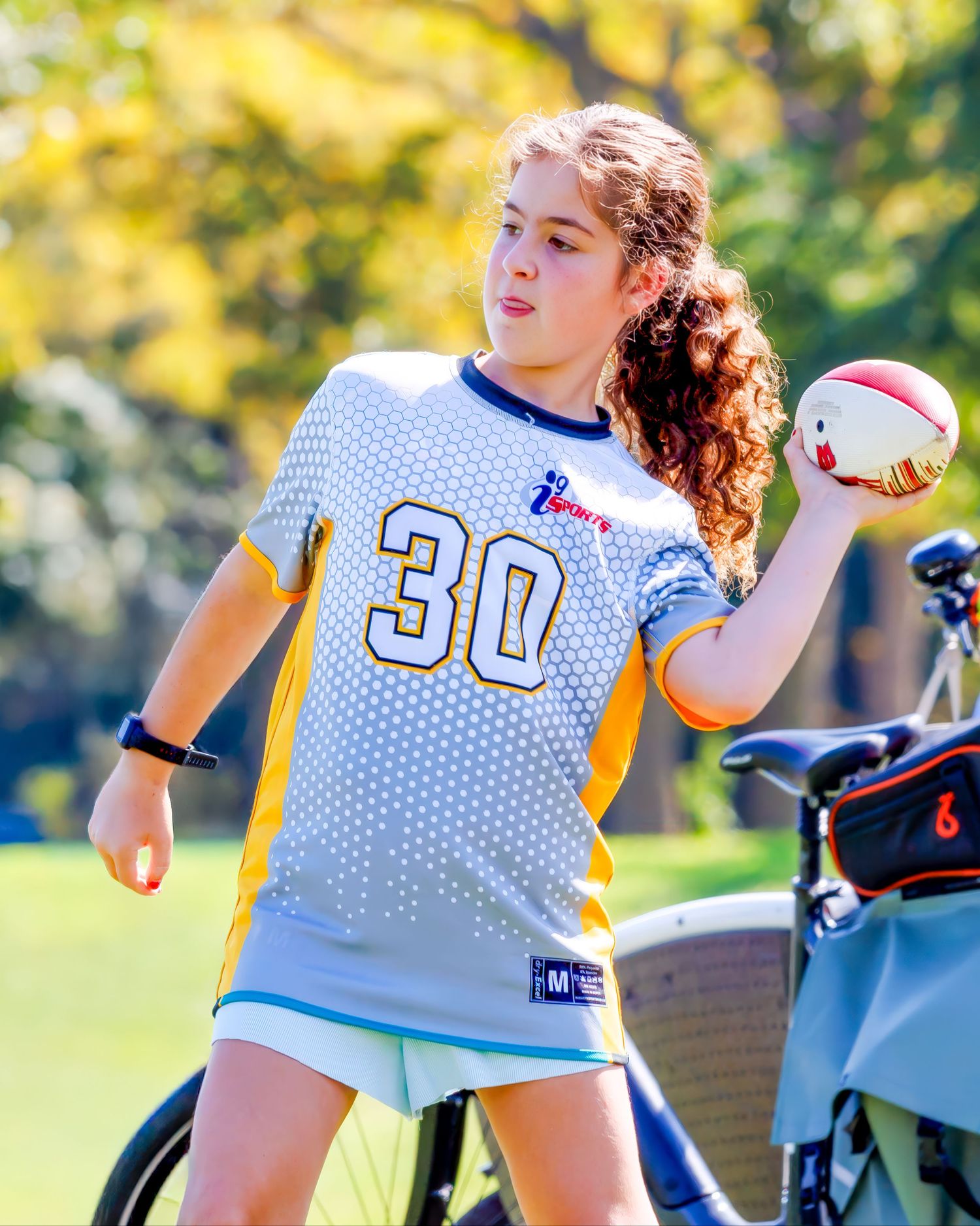 Flag football players in white jerseys compete on a sunny autumn day during an outdoor game.