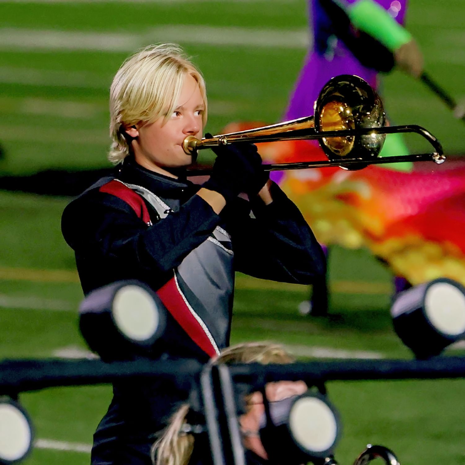 Marching band member plays trombone during performance on field.