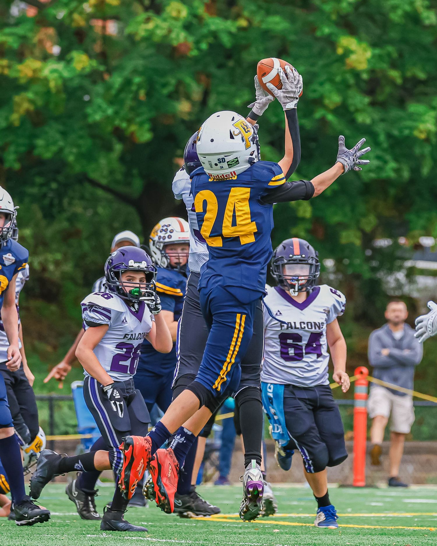 Football players engage in an intense play on the field with one player leaping high in the air during a game.