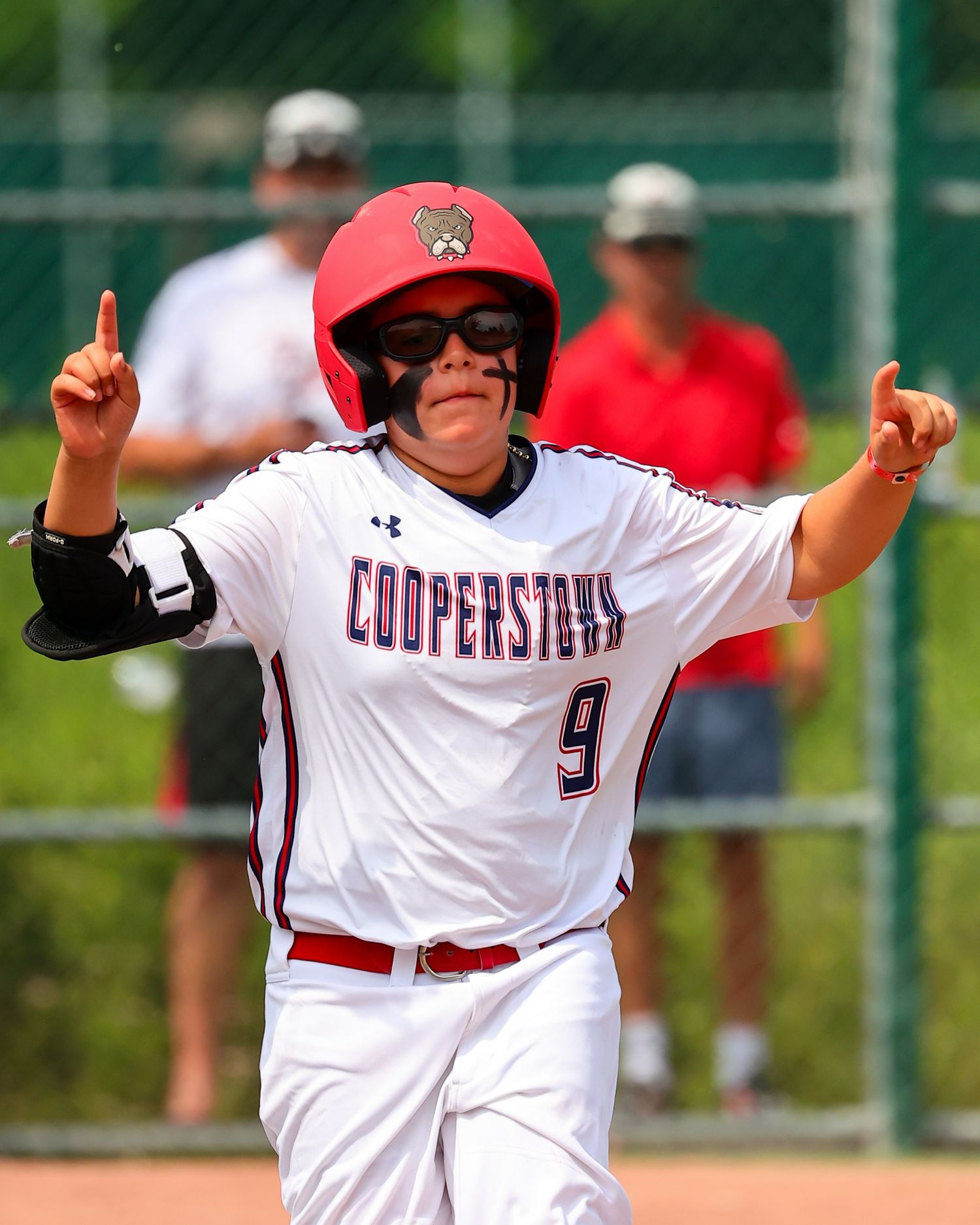 Baseball player in white uniform with red accents raises arms in celebration during a game.