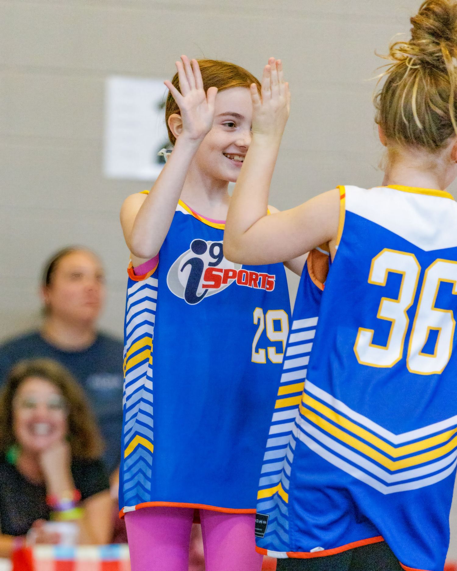 Two basketball players in blue and white jerseys with numbers 29 and 36 celebrate during a game.