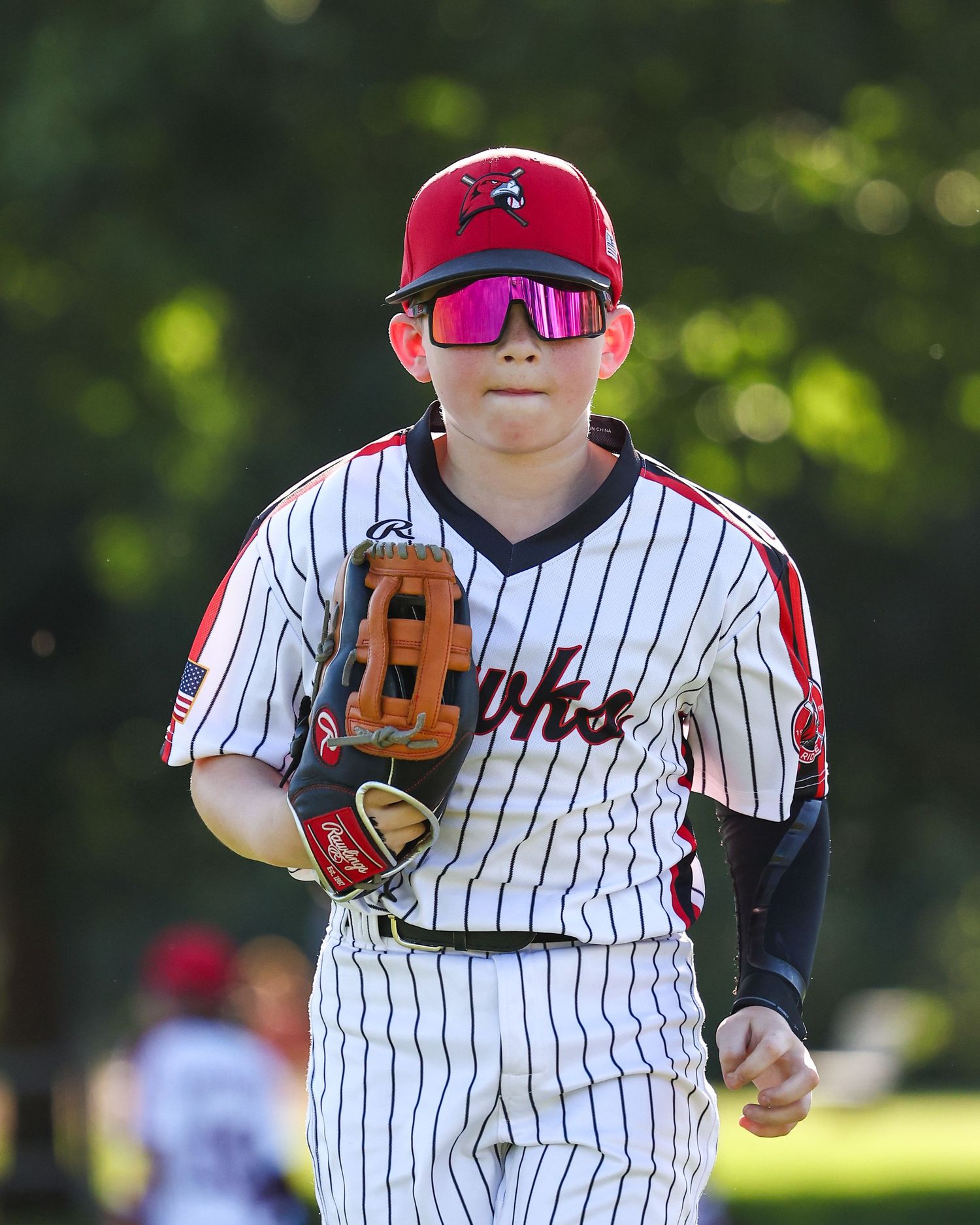 Baseball player in pinstriped uniform and red cap wears reflective sunglasses.