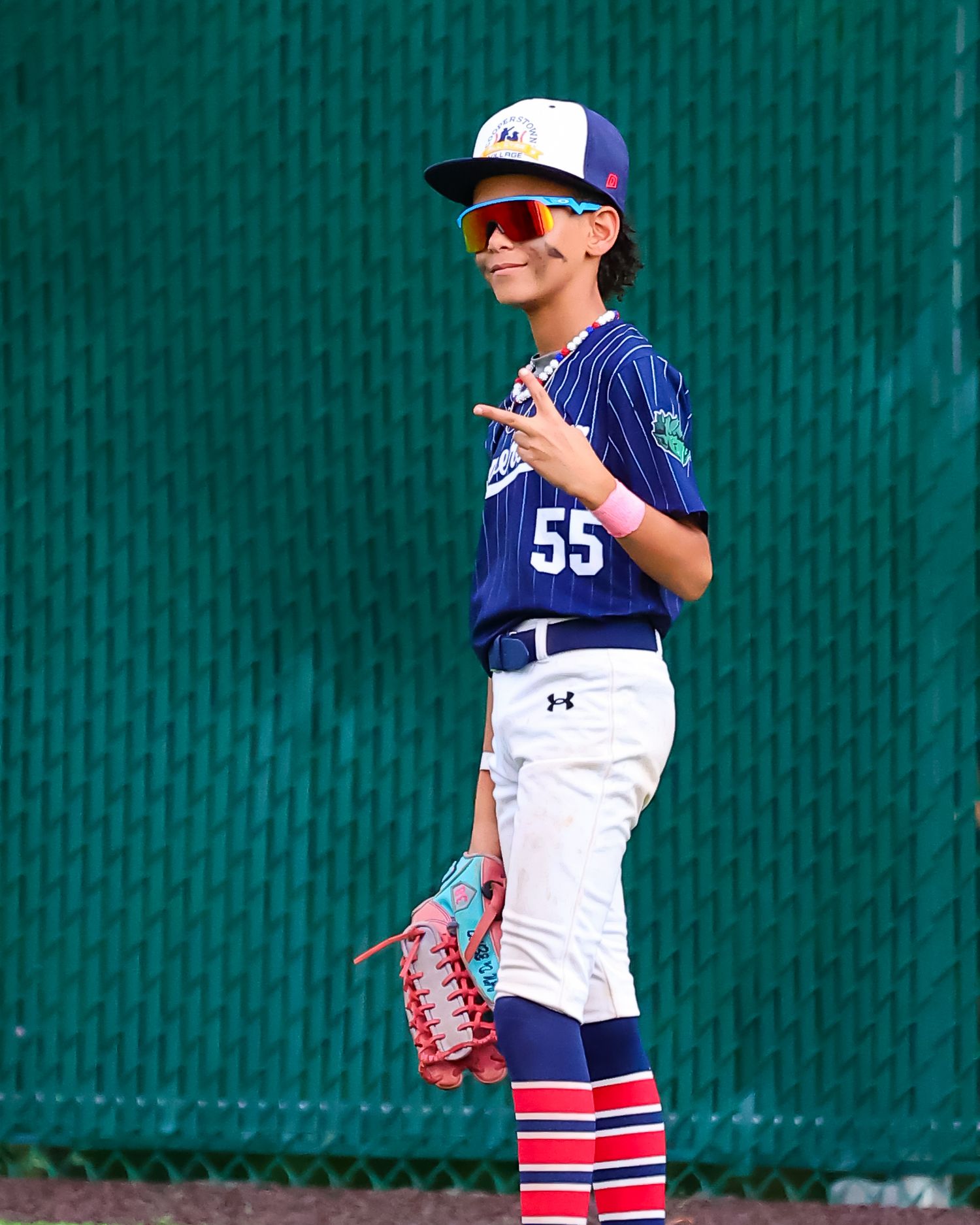 Young baseball player in blue and white uniform stands in ready position on field with striped socks.