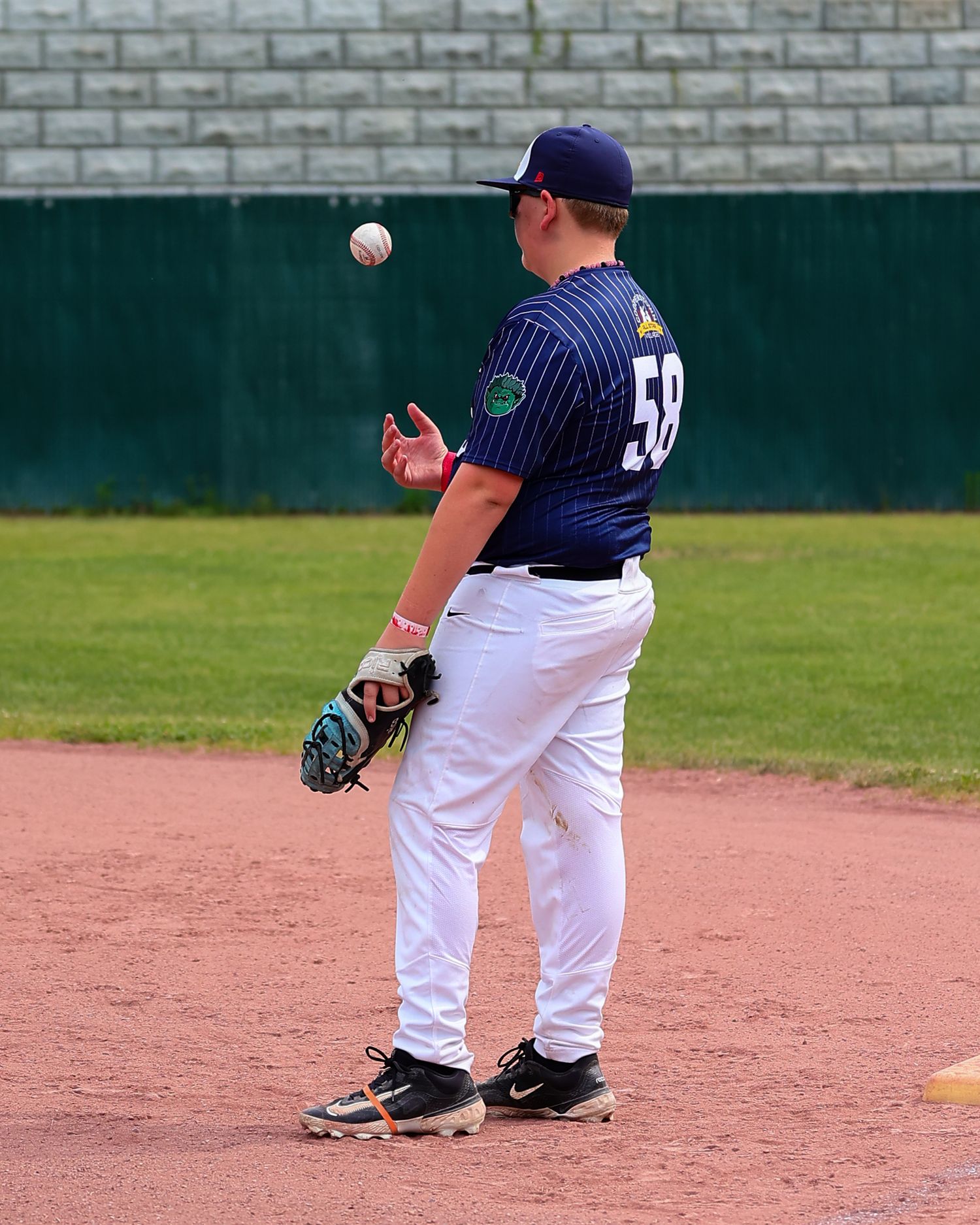 Baseball player in pinstripe uniform wearing number 59 tosses a baseball on the infield dirt during a game.