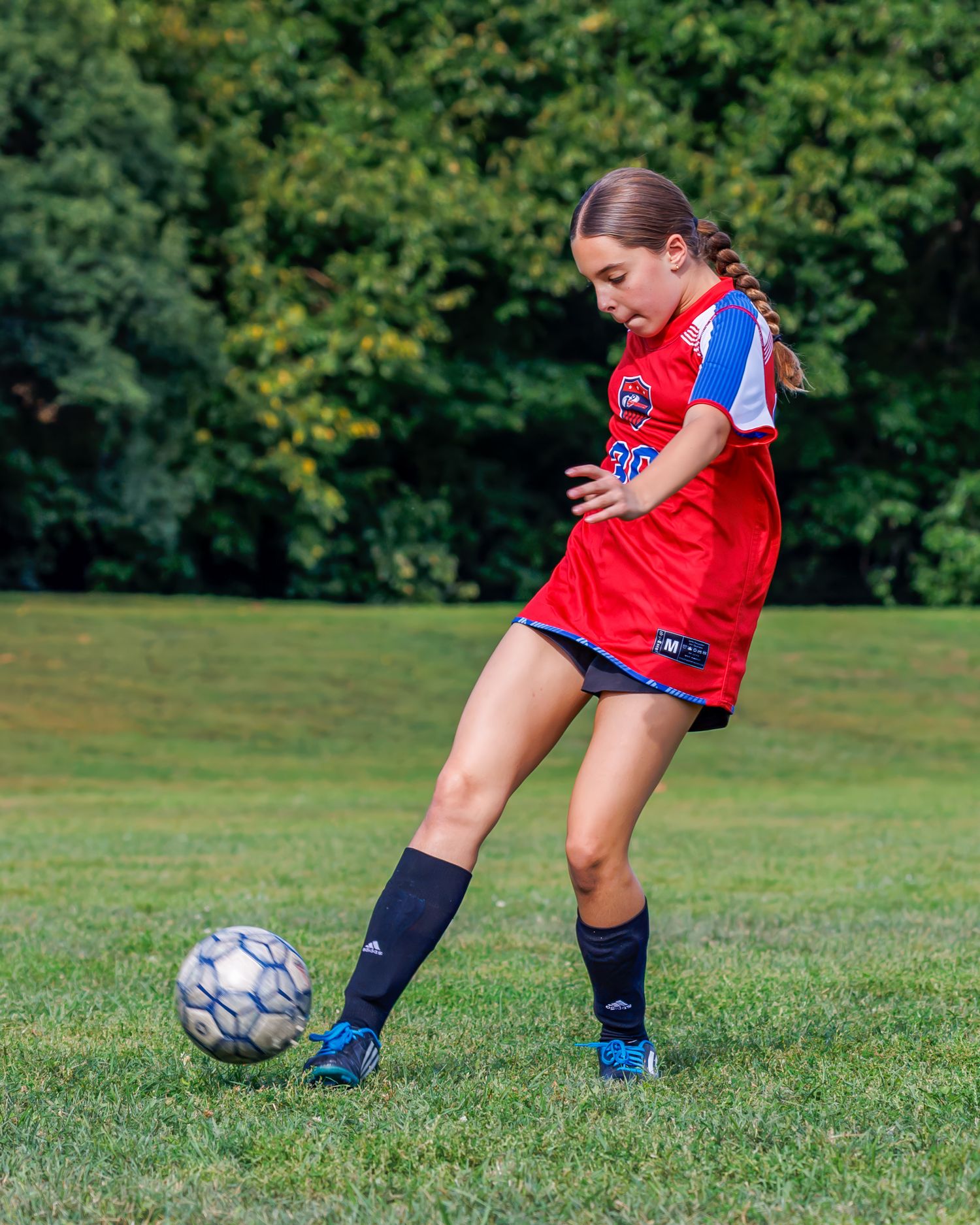 Close-up sequence showing soccer player's feet dribbling and kicking a ball on green grass field.