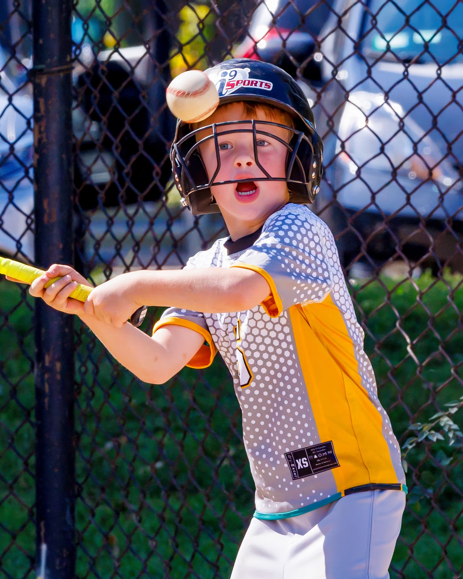 A baseball player in a yellow and white uniform swings a bat during a game.