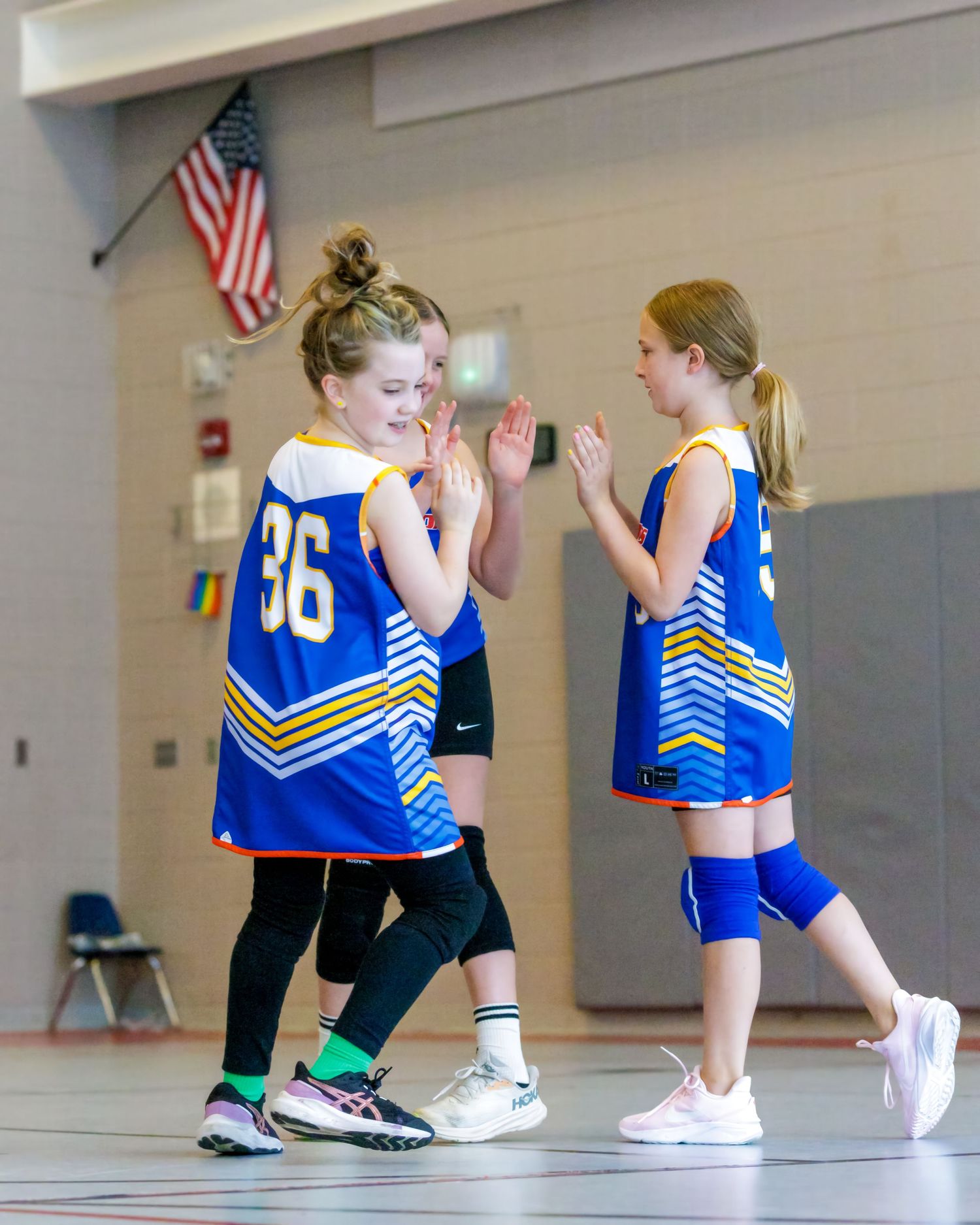 Athletes in blue and black uniforms stretch together in a gym before practice.