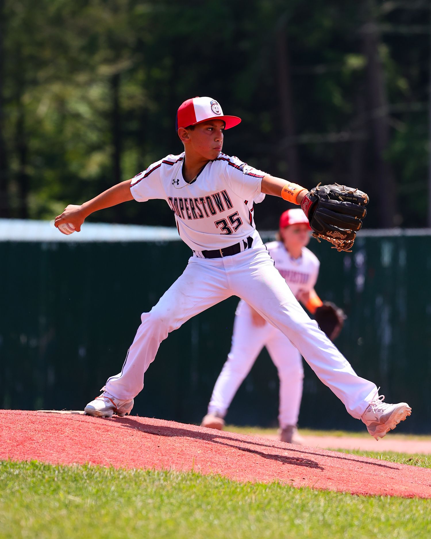 Baseball players in white uniforms making diving defensive plays on a sunny field during a game.