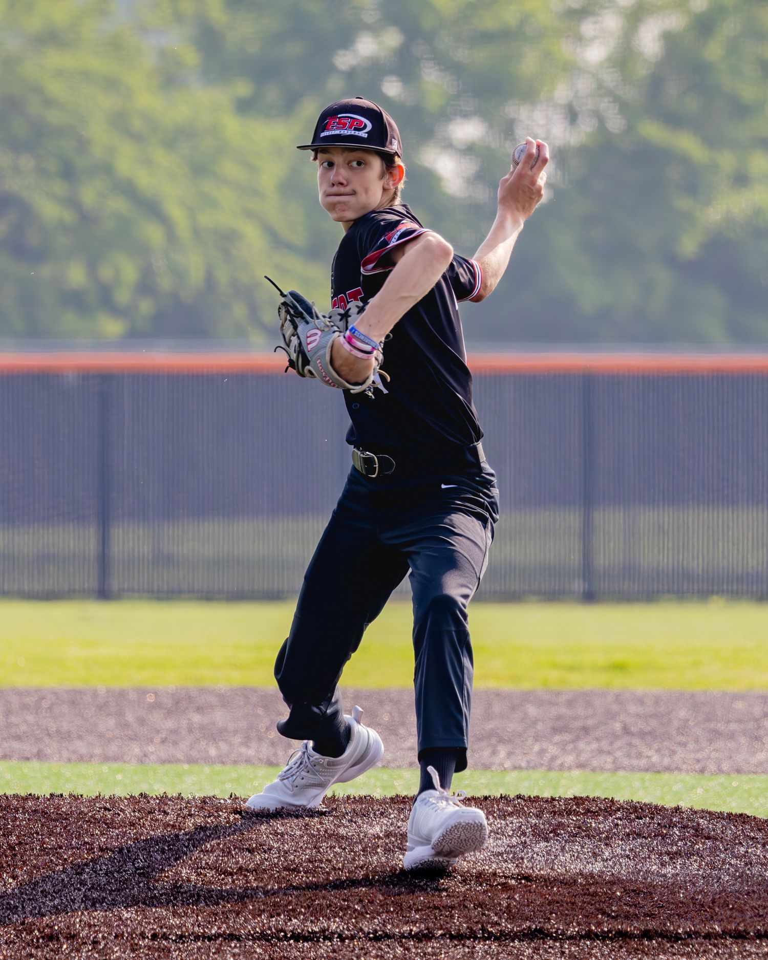 A baseball pitcher shown in sequence throwing a pitch from the mound on a sunny day at the ballfield.