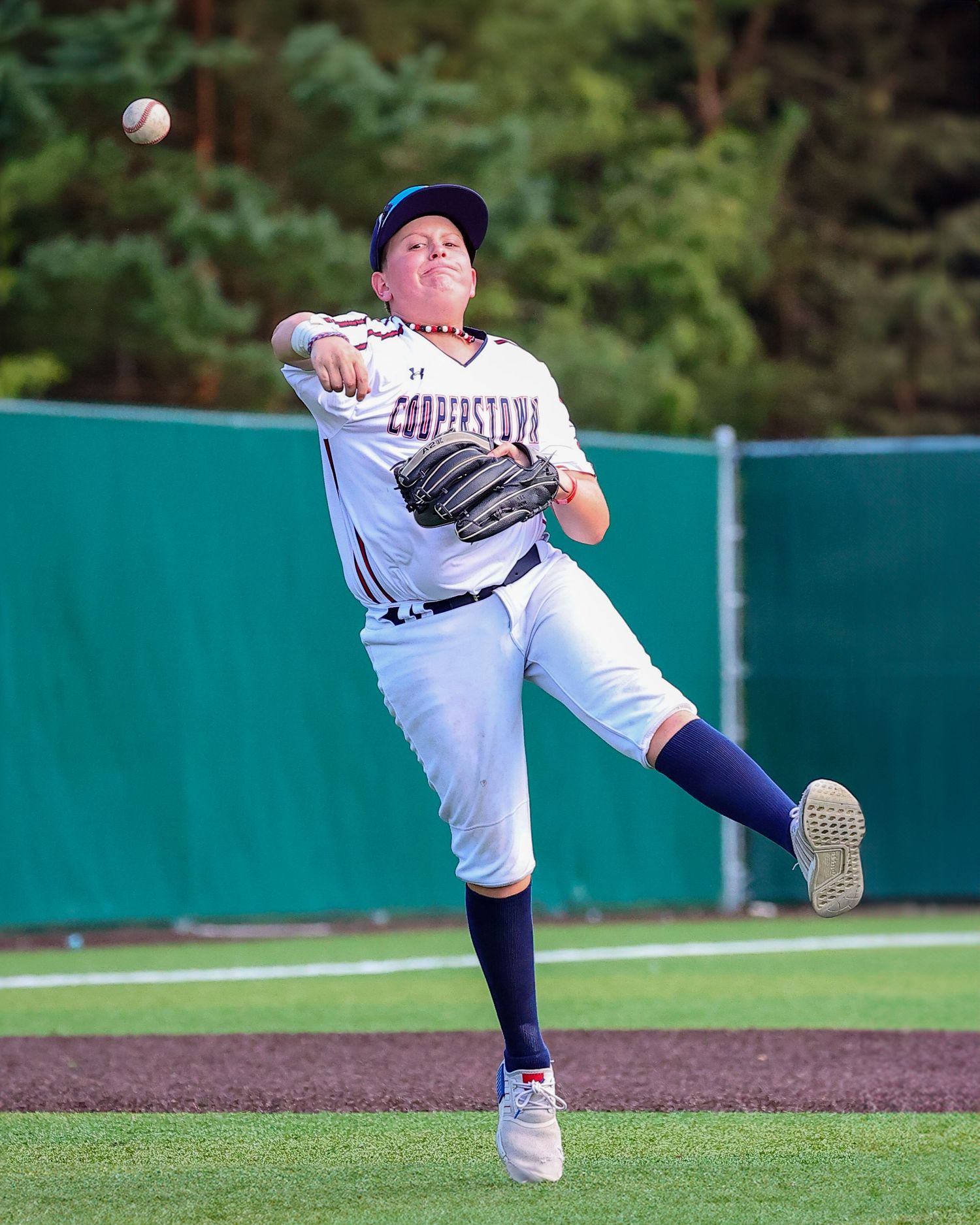 A baseball pitcher shown in three sequential frames delivering a pitch from the mound on a sunny day.