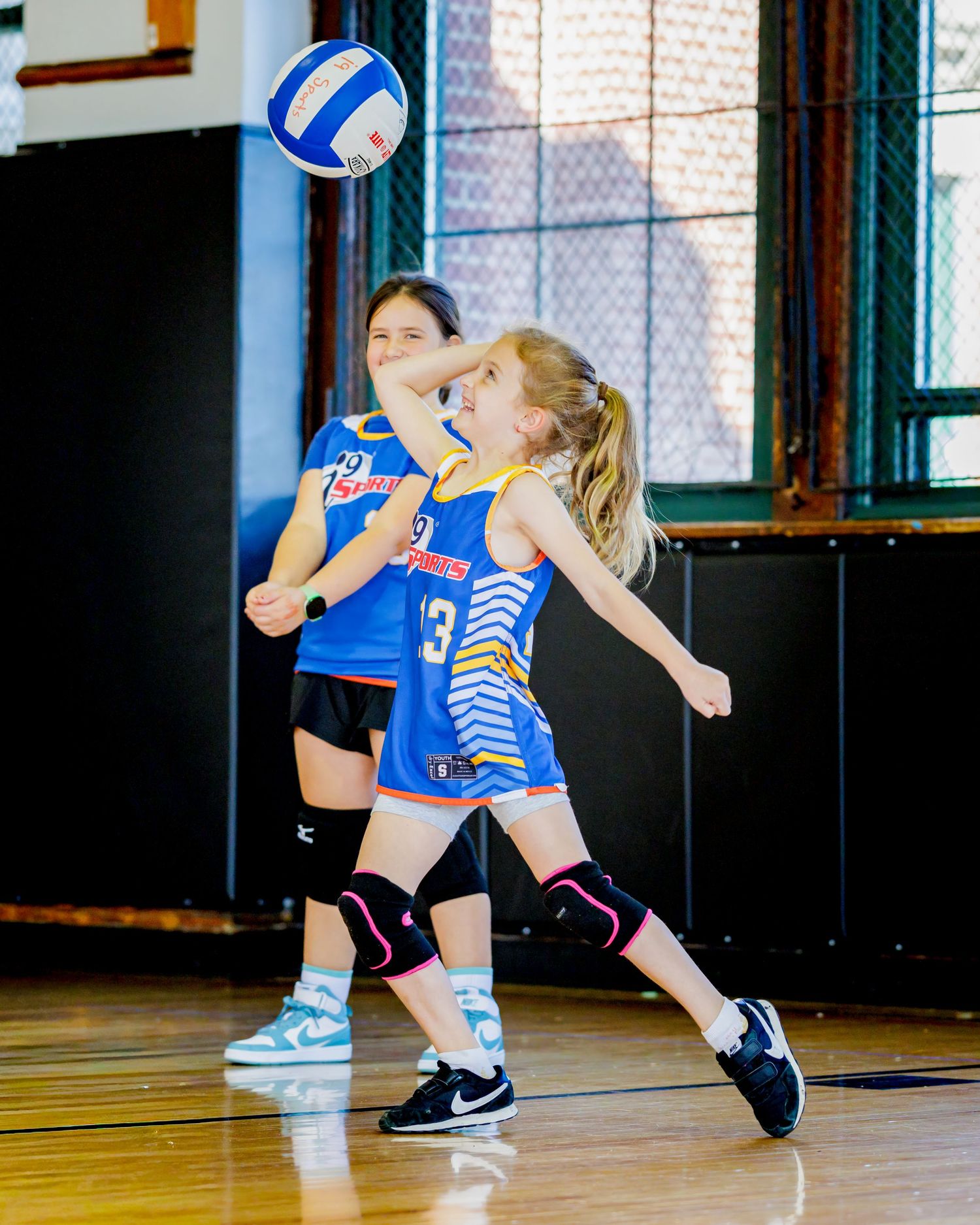 Sequence of volleyball player diving to save a ball during indoor match, showing athletic movement in blue uniform.