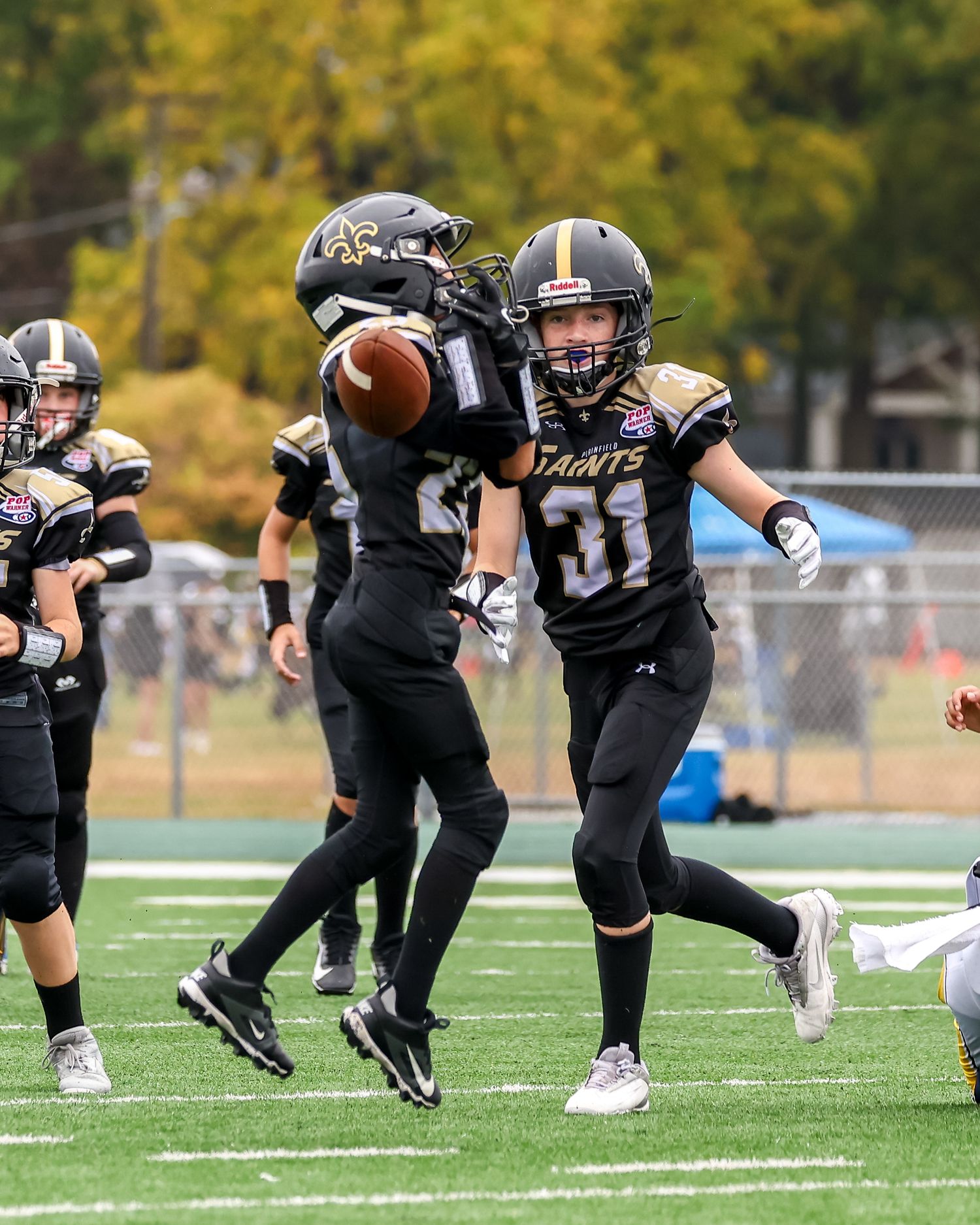 Two Saints football players in black uniforms celebrate on the field during a game.