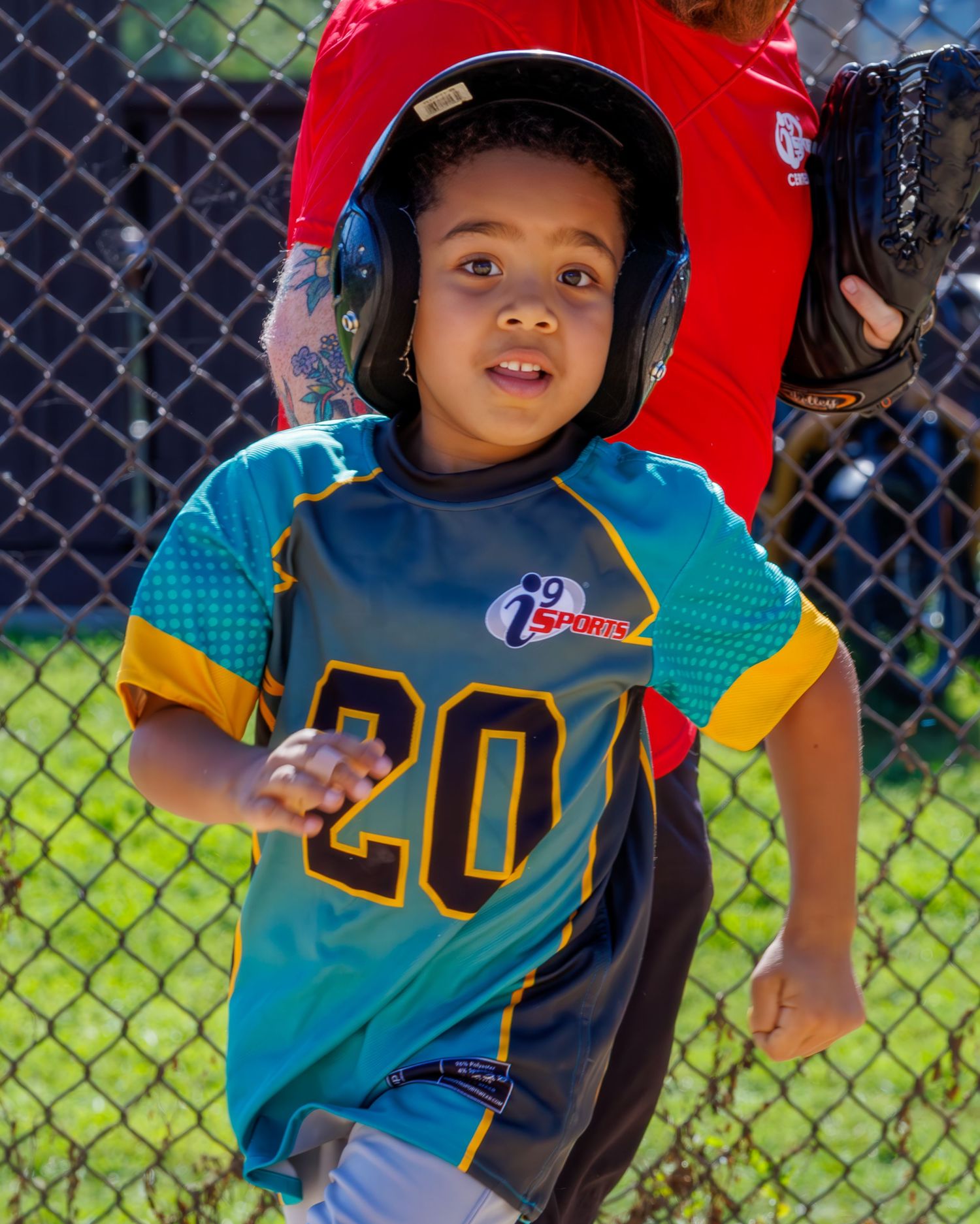 Young baseball player in a navy jersey and batting helmet stands ready at the batting cage during practice.