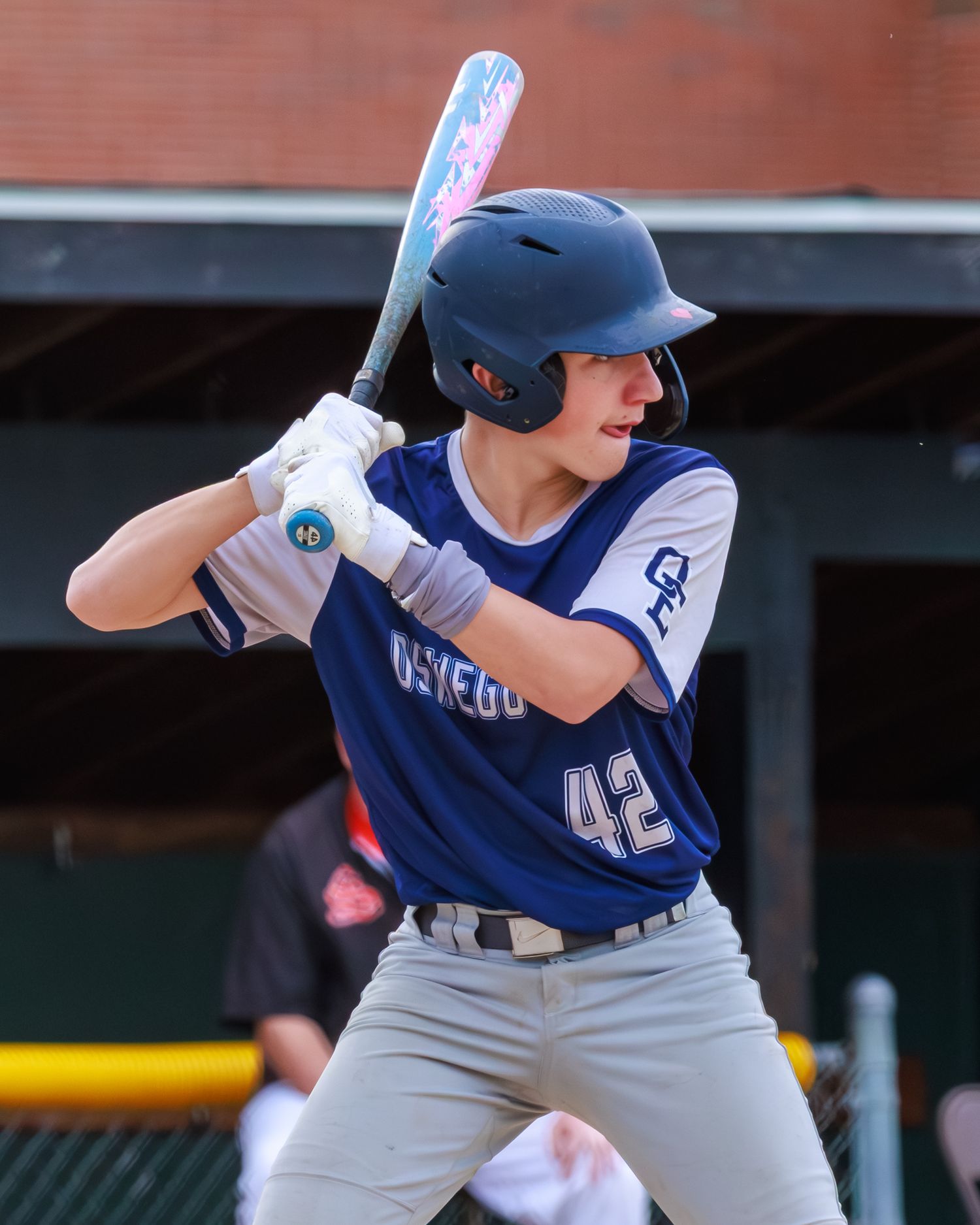 Baseball player #42 in blue Oswego uniform stands at bat wearing helmet, ready to swing during a game.