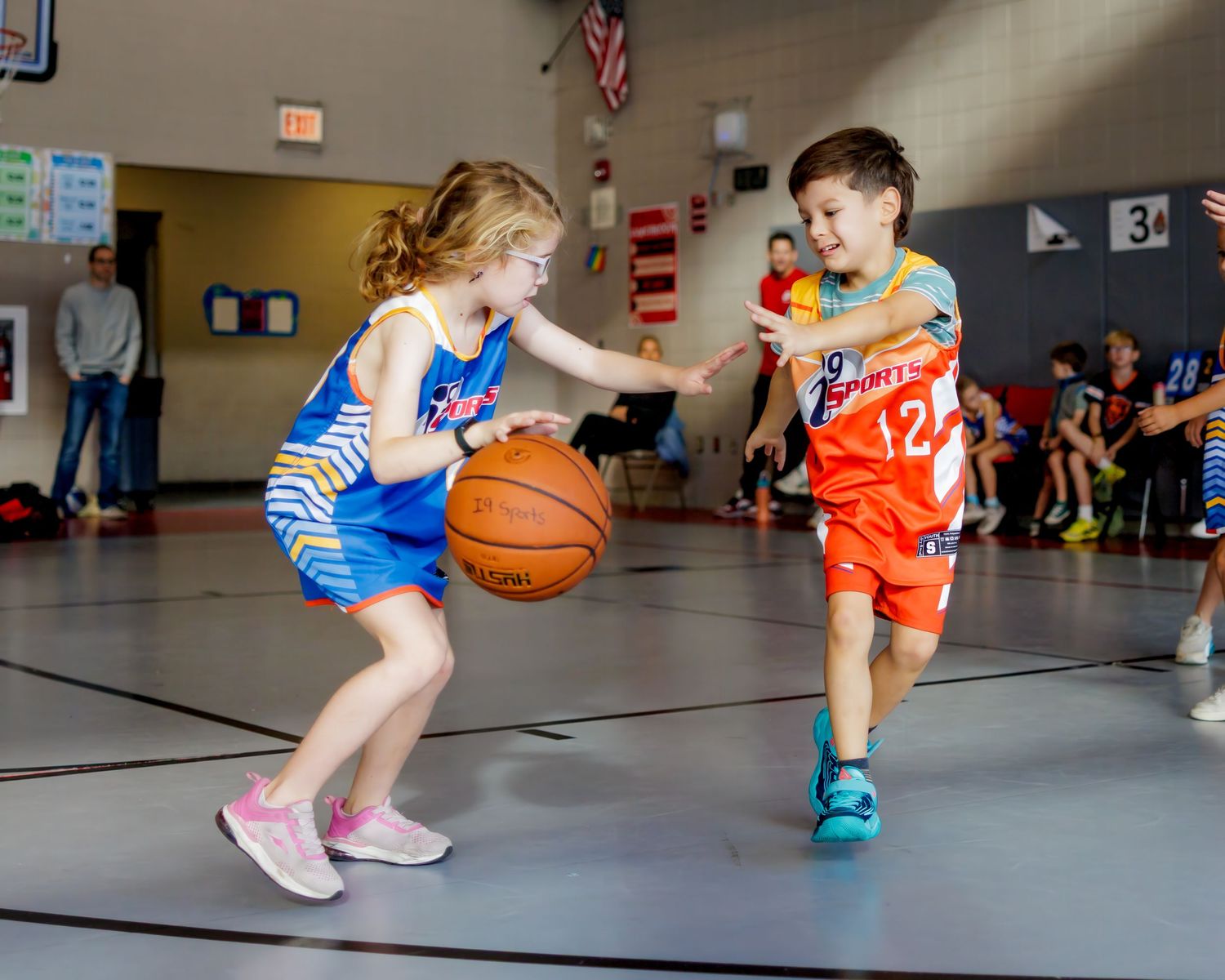 Young players dribble basketballs in a gym during a youth basketball practice session.