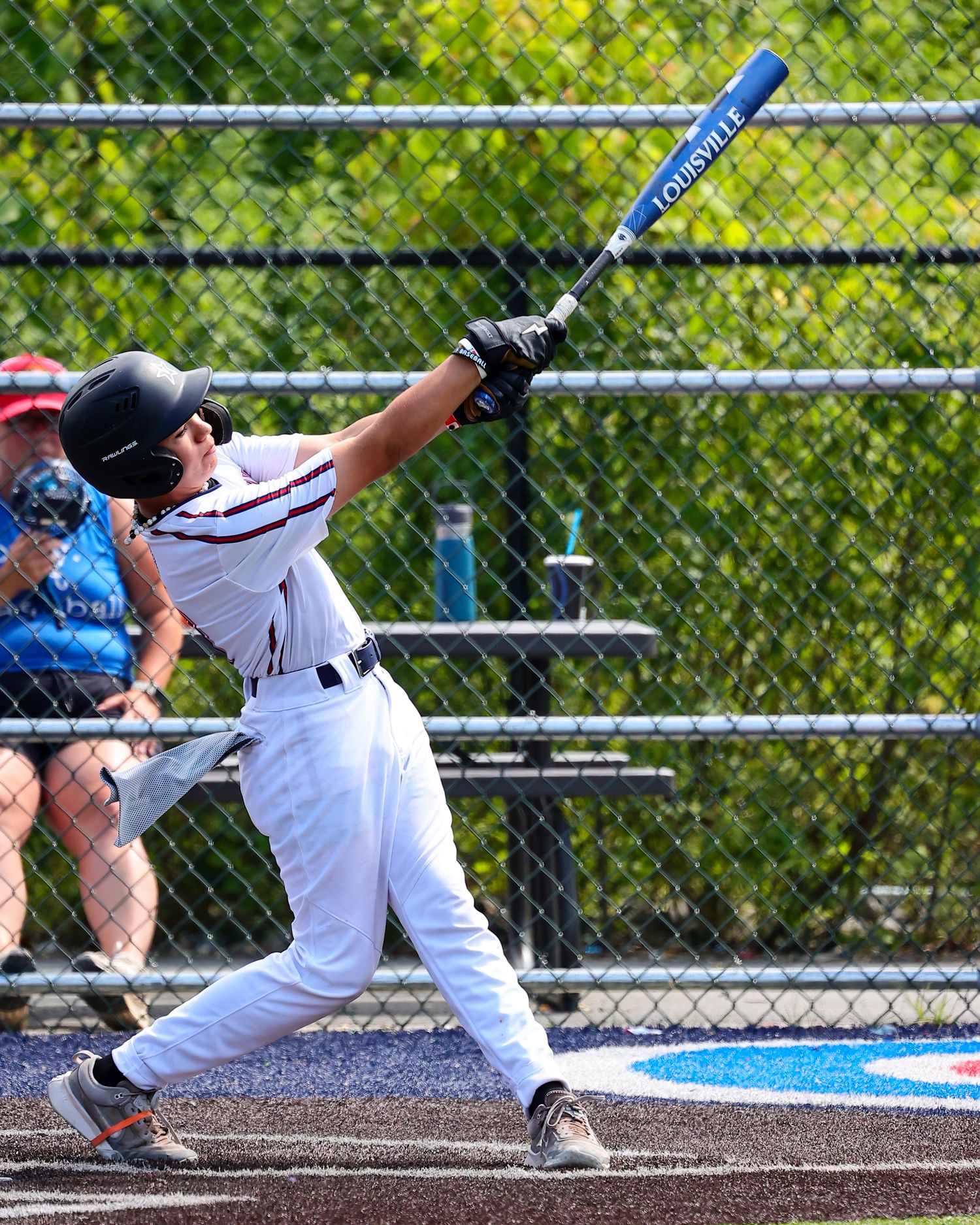 Baseball player sliding into base during game on dirt infield with dramatic cloud of dust rising up.