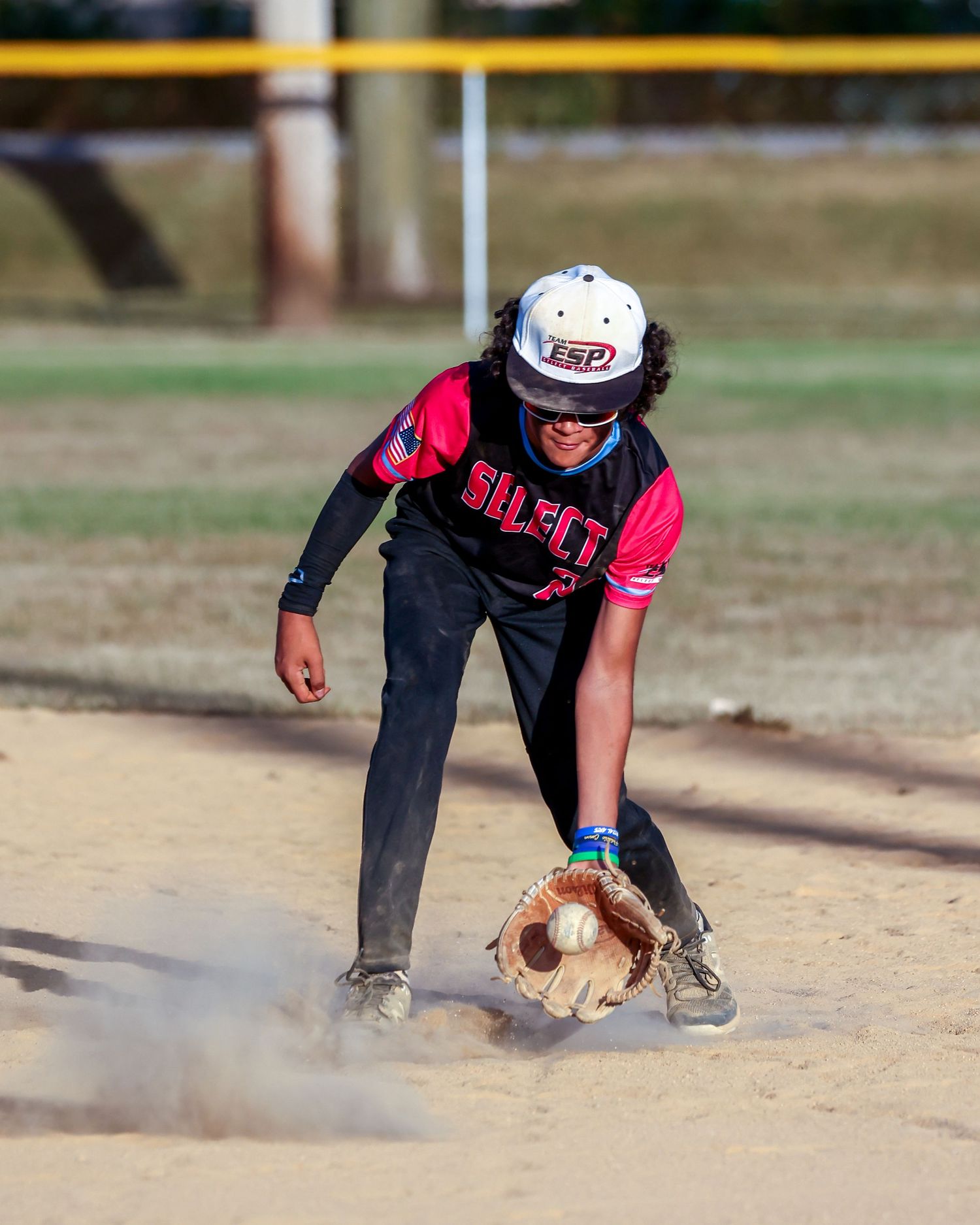 A baseball infielder making a diving catch near the base.
