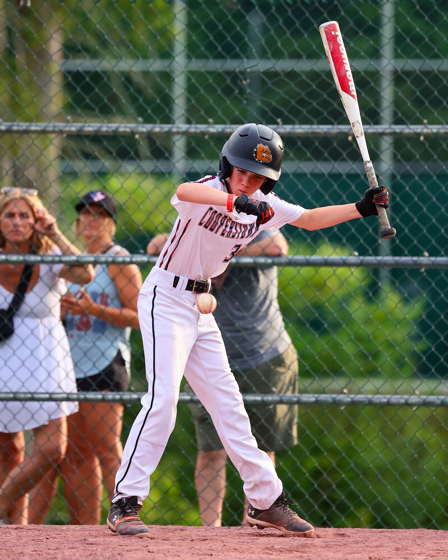 Baseball player in white uniform performs a bunting motion at home plate during a game.