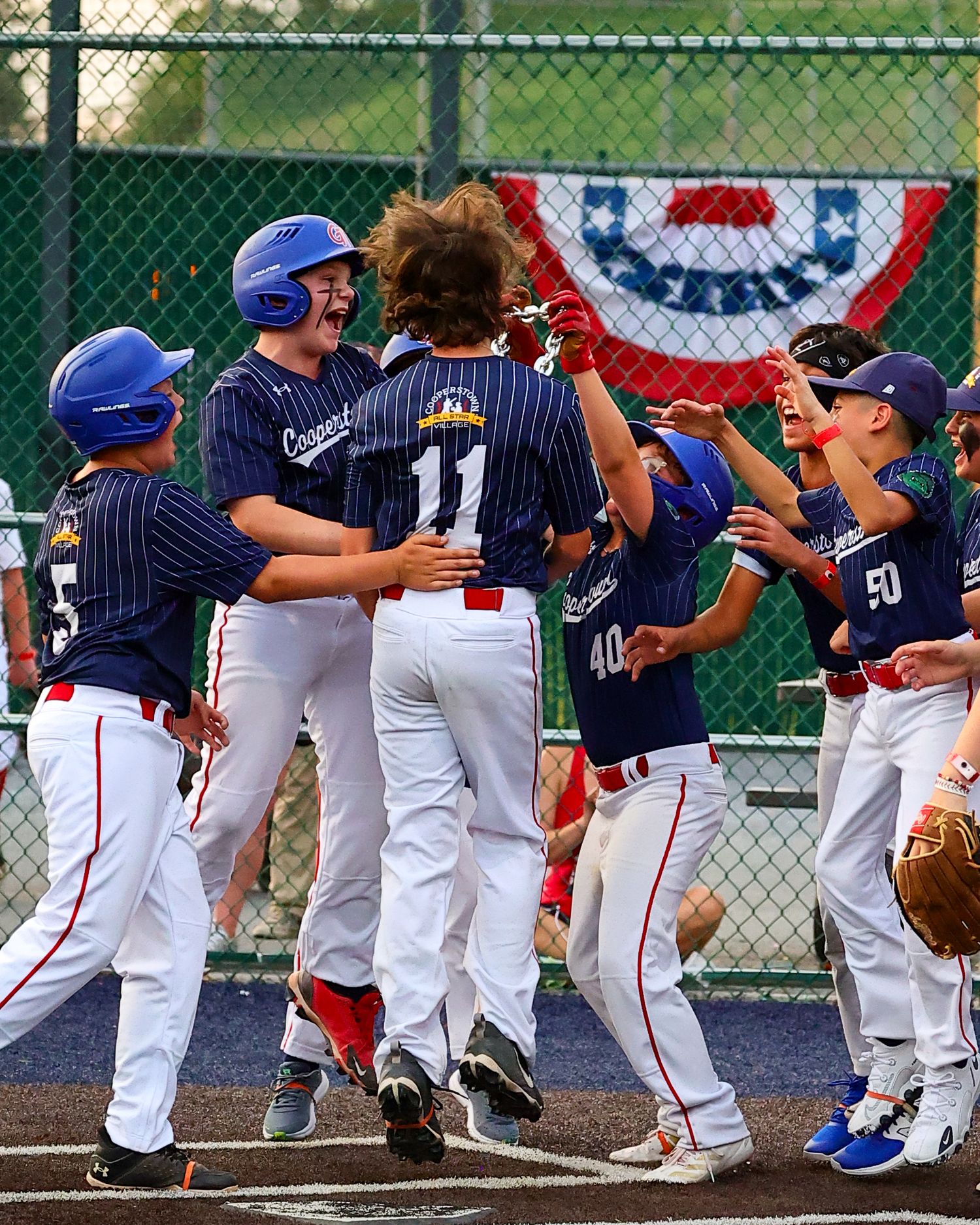 Baseball players in navy pinstripe uniforms and white pants line up along a fence during a game celebration.