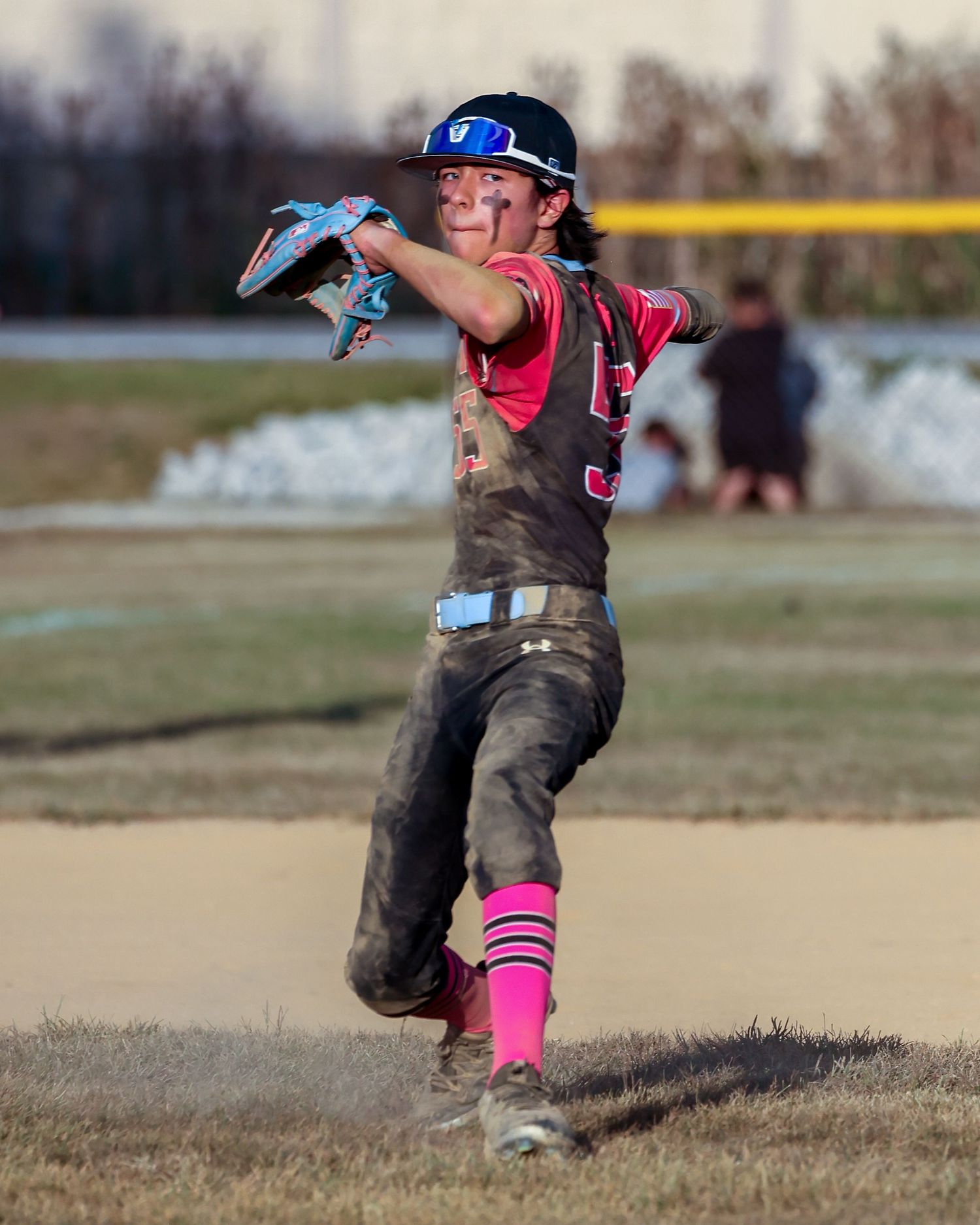 A baseball player throwing a ball with dirt kicking up around their feet.