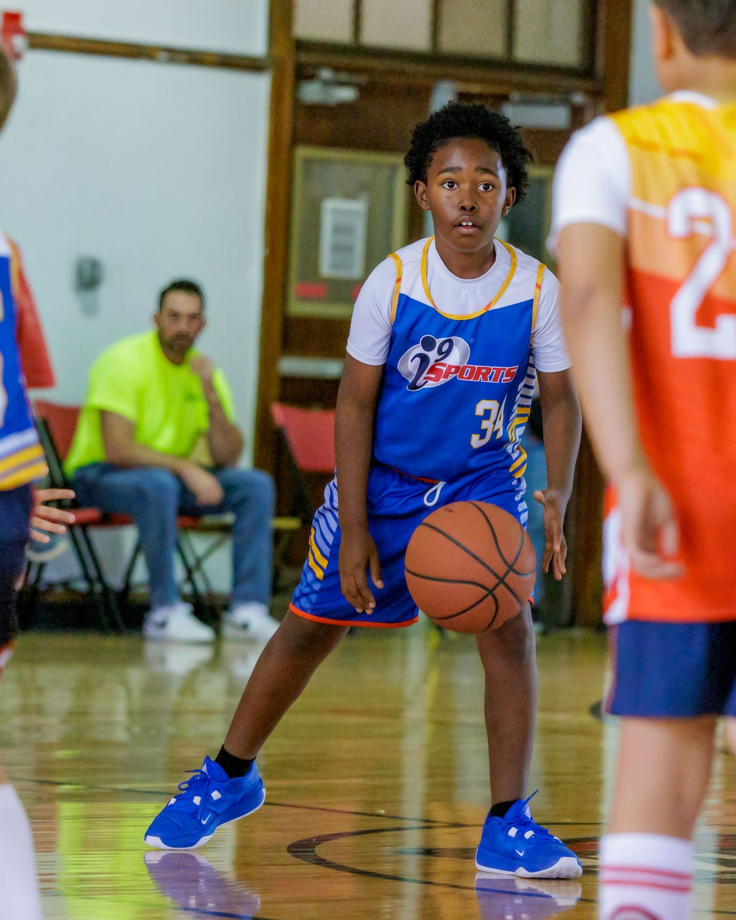 Young basketball player in blue jersey dribbling during an indoor youth league game.