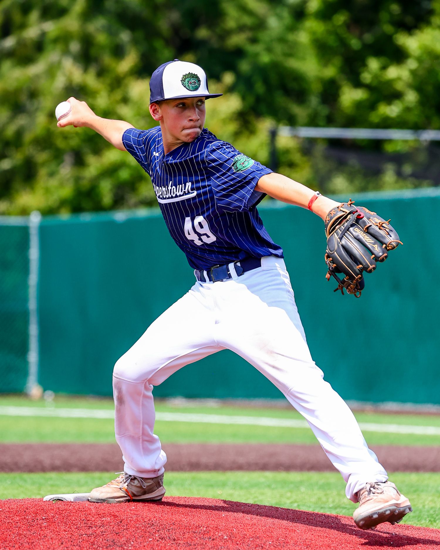 Baseball player in white and navy uniform stretches to make a defensive play on the infield during a game.