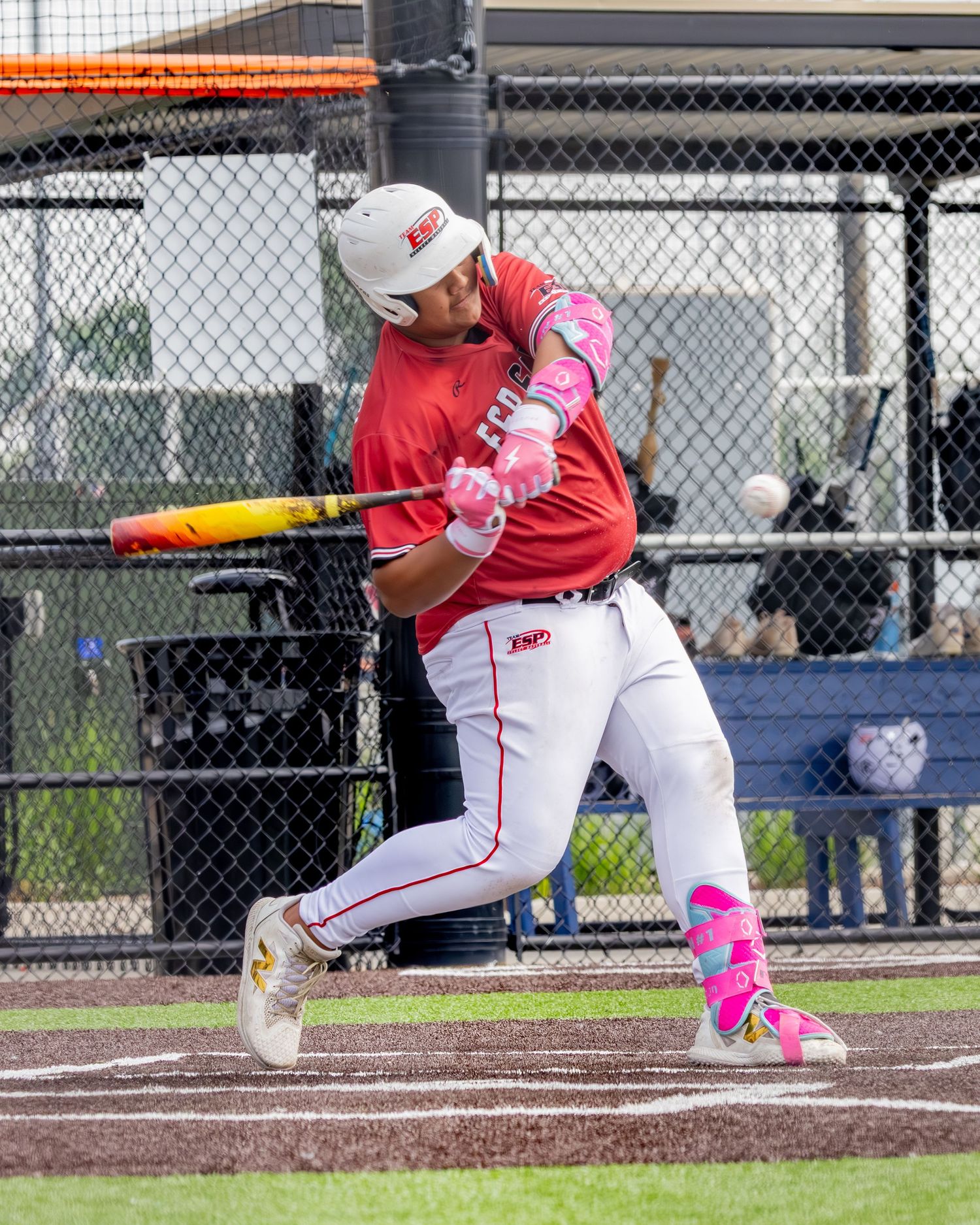 Baseball player in red uniform with pink socks performs a sliding bunt maneuver during a game.