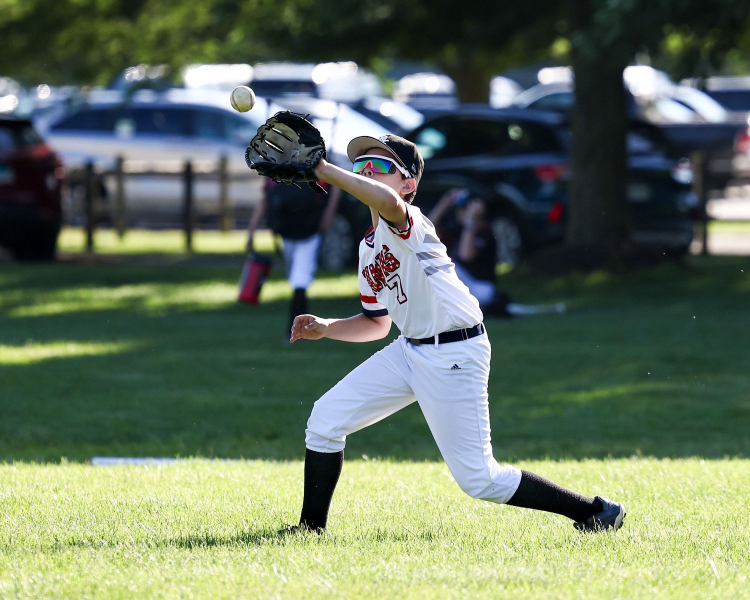 Baseball players fielding fly balls during a game on a sunny day.