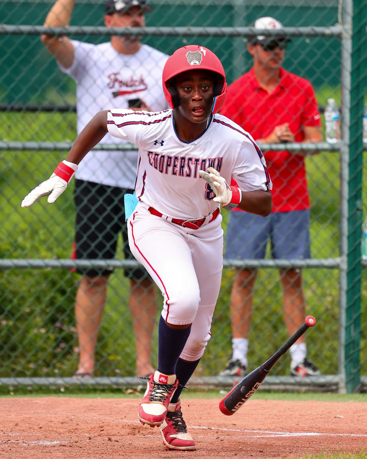 Baseball player in red uniform performs a bunting motion during a game on a sunny day.