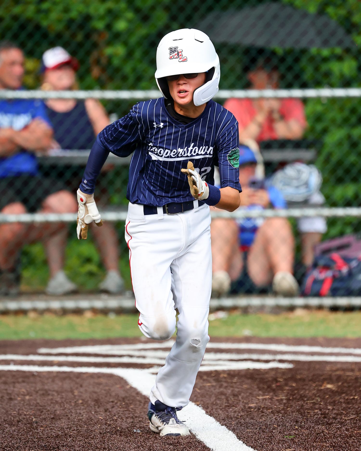 Baseball player in pinstripe uniform running on baseline during competitive game on turf infield.