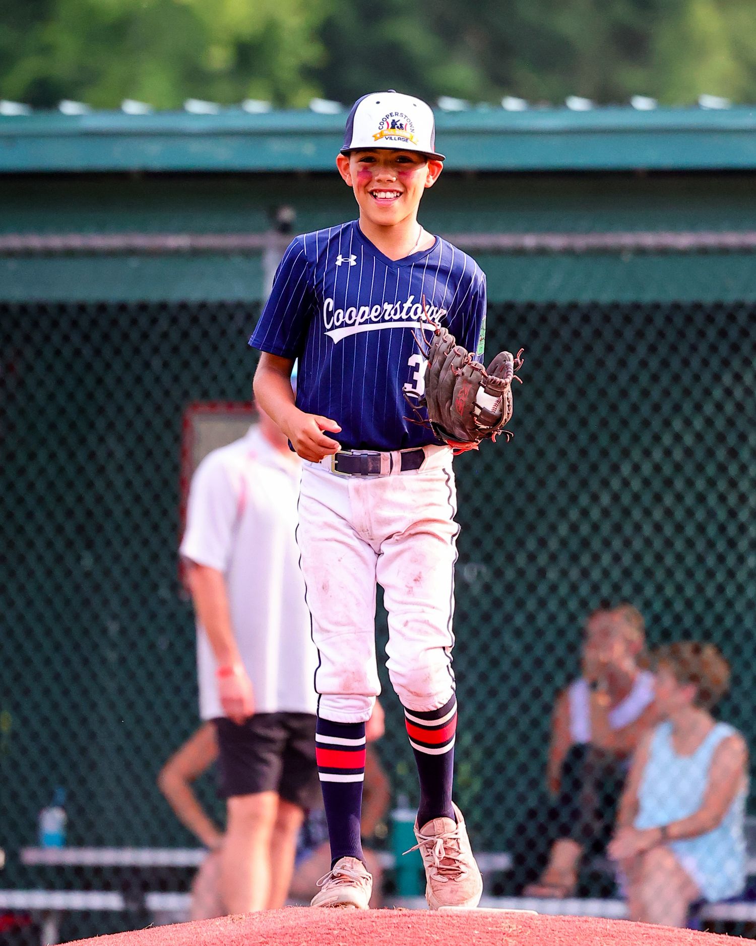 Baseball player in navy uniform pitches from the mound during a game.