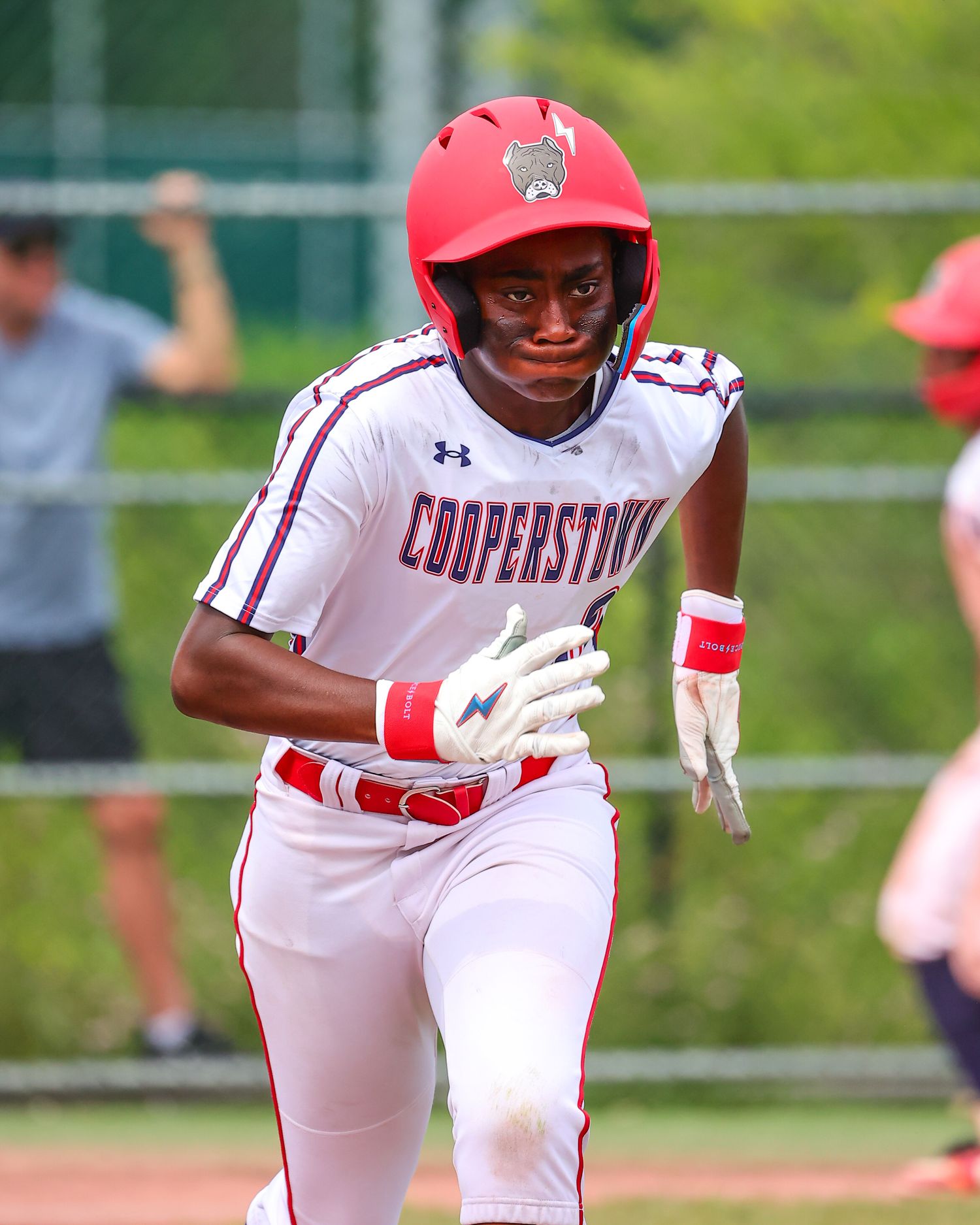 Baseball player in white uniform with red accents swings bat during game on sunny day.