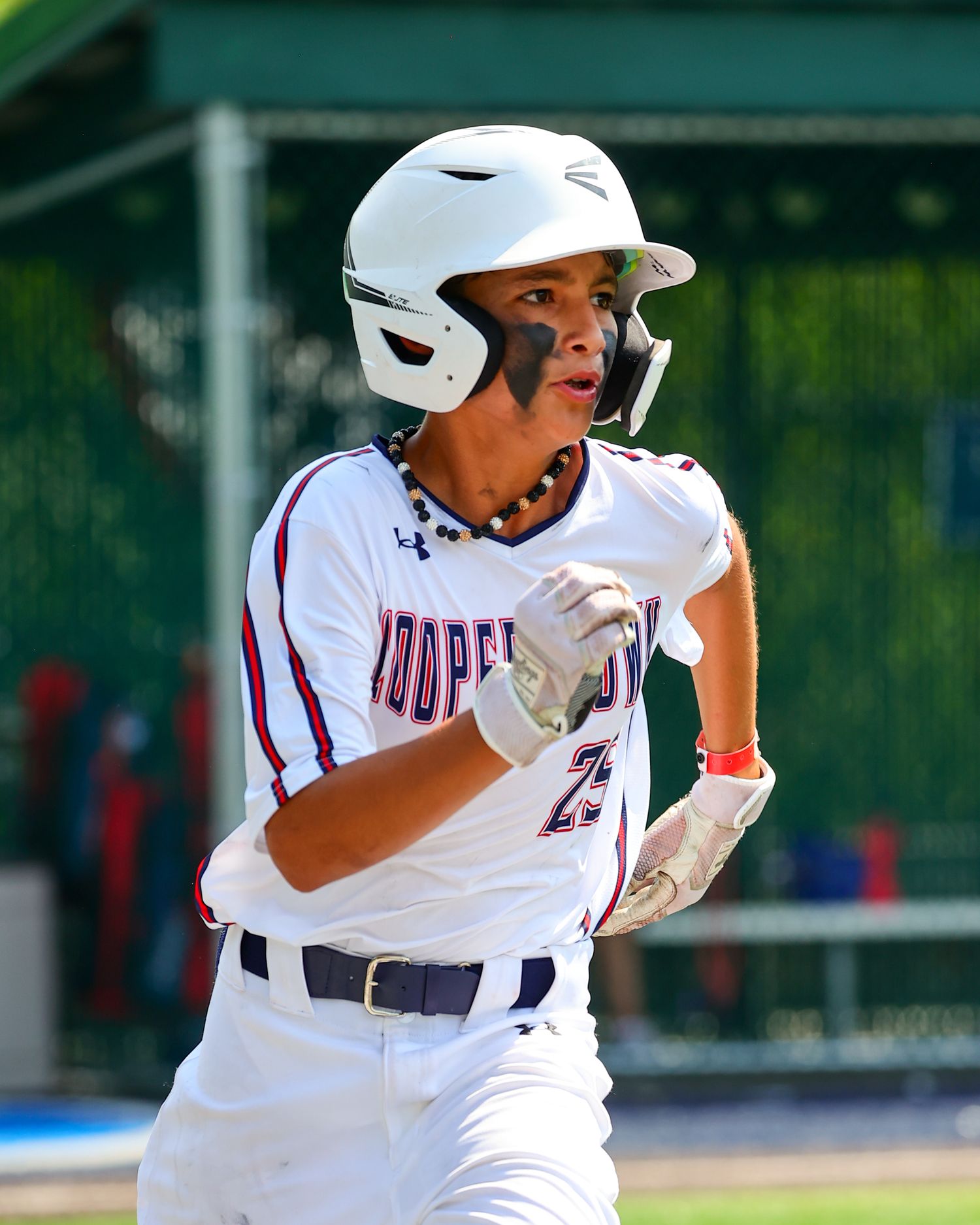 Baseball player in white uniform swings bat during game with intense focus and concentration.