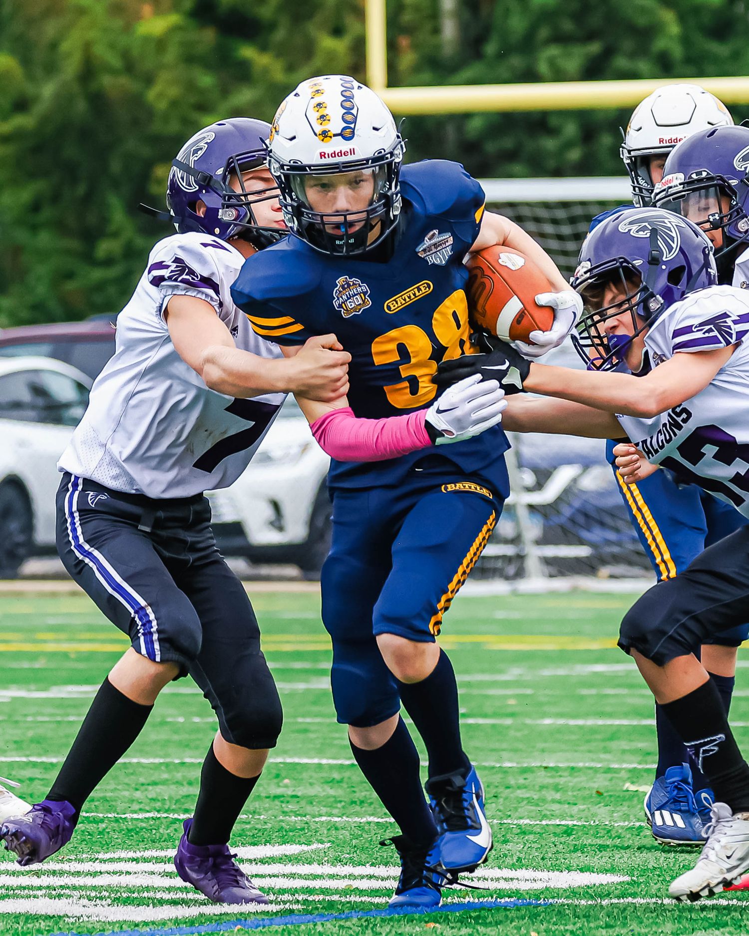Player in blue jersey breaking through defensive tackles during youth football game.