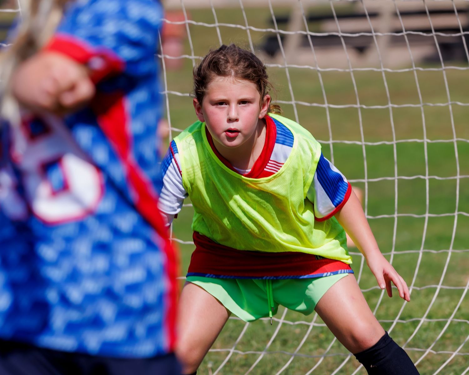 Soccer player in bright yellow training vest jumps to make a save during practice session.