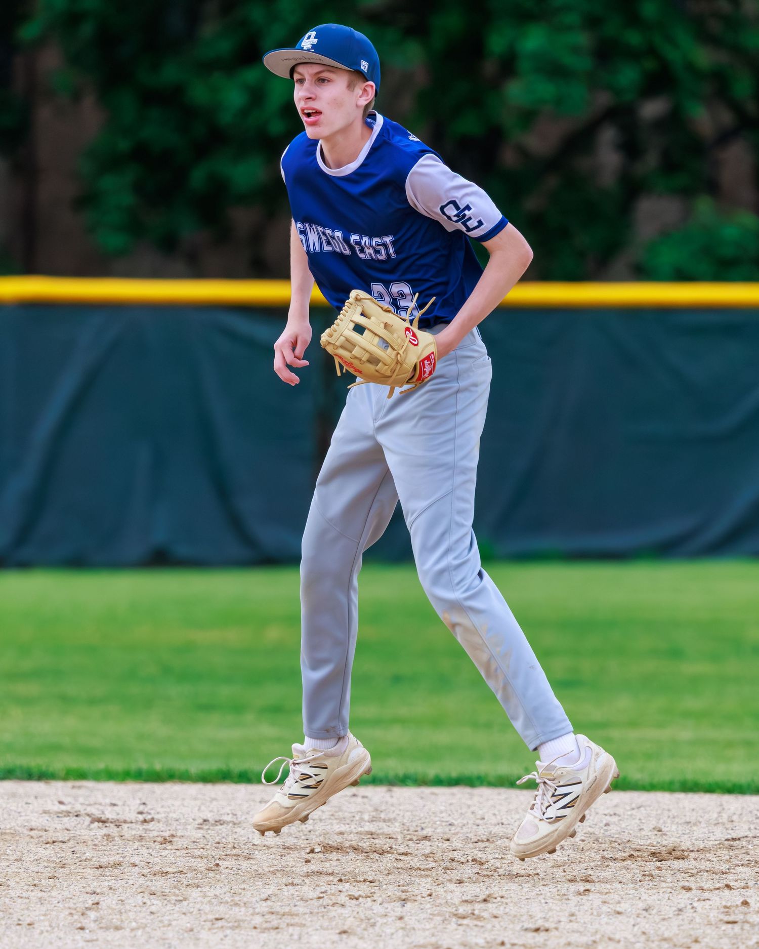 Young baseball player in blue uniform jogging on field with glove during youth league game.