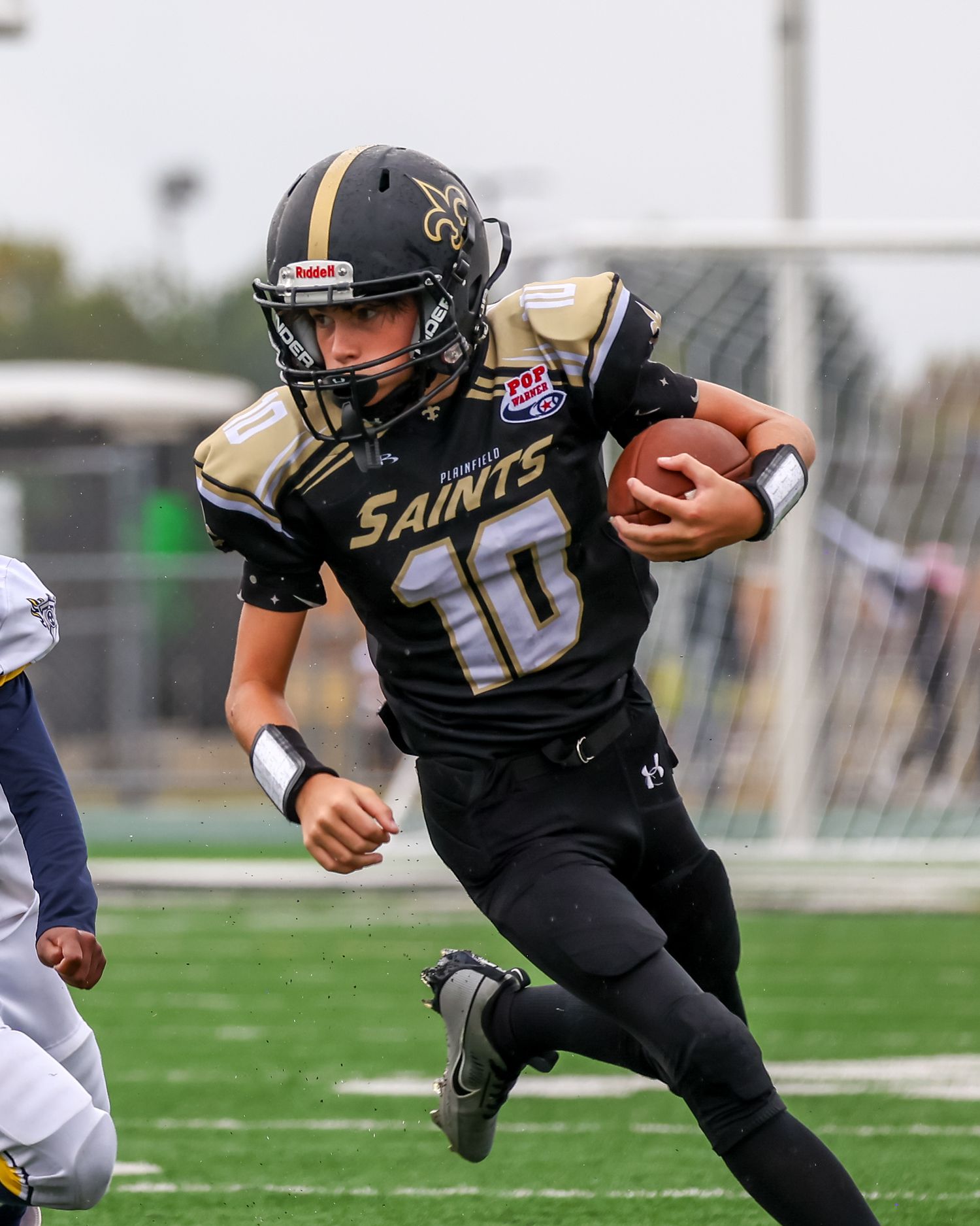 Saints player in black uniform number 10 running with football during game.
