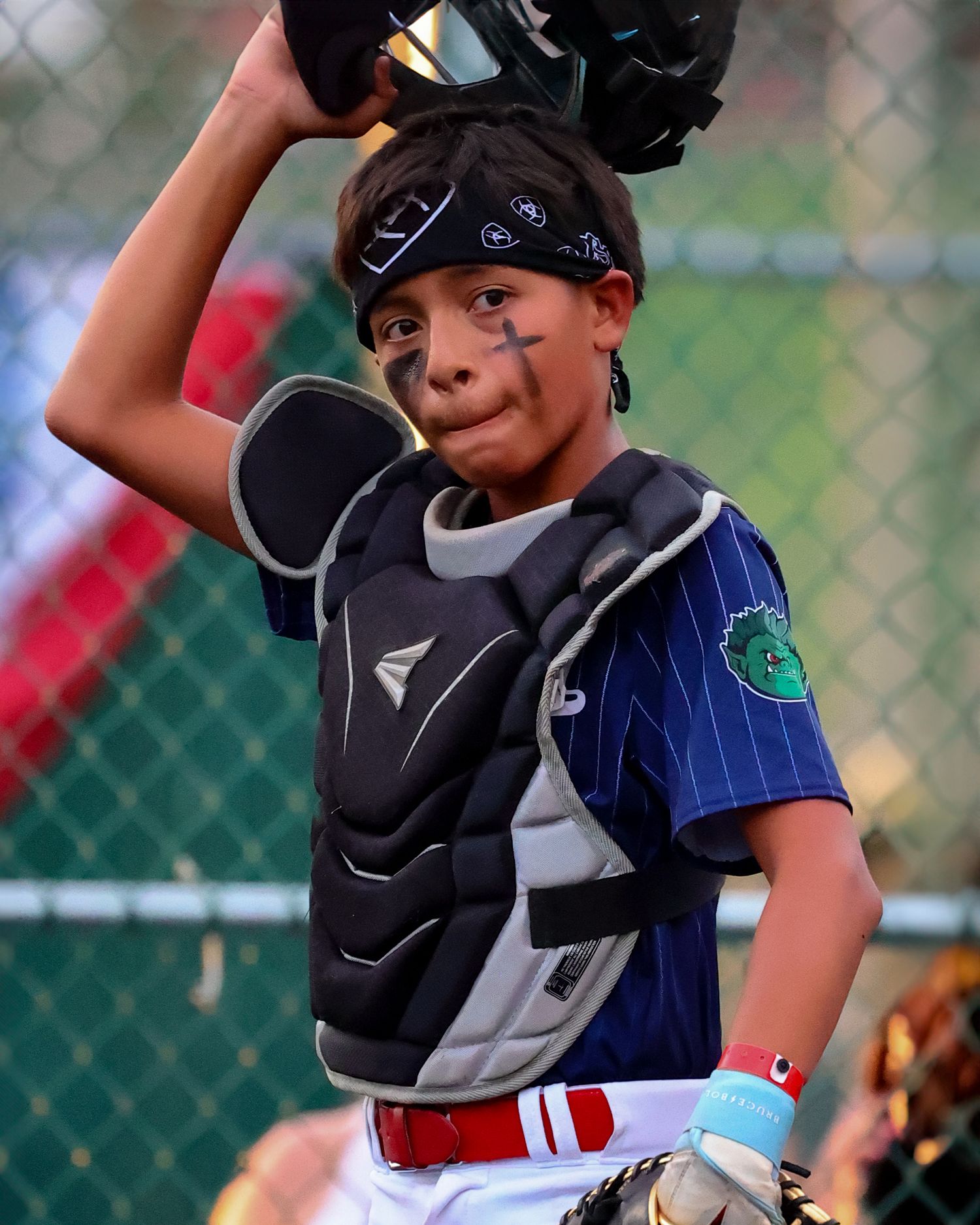 A young baseball catcher in protective gear crouches behind home plate during a youth baseball game.