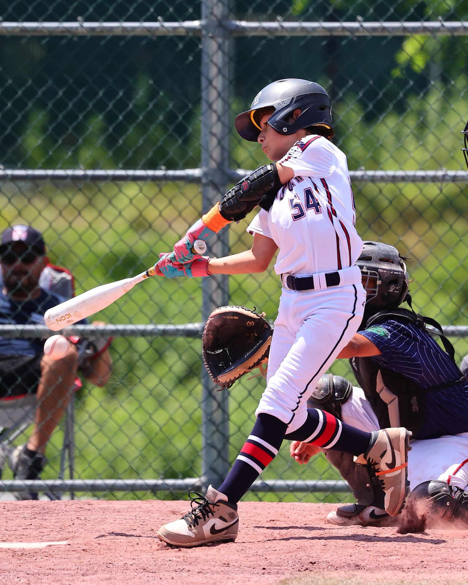 Baseball player slides into base during an intense game as catcher attempts to make the tag.