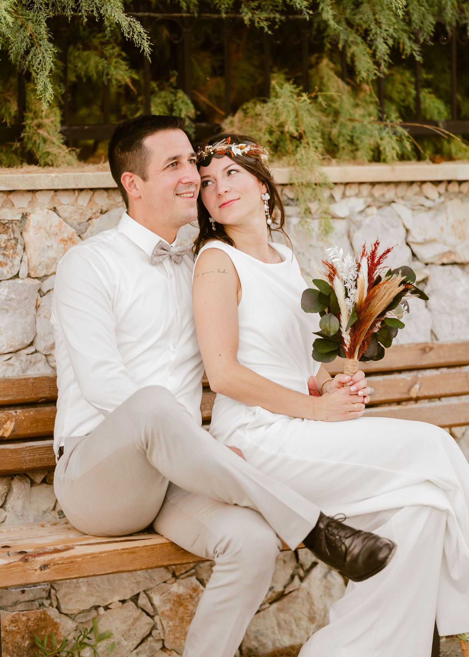 Ein Paar teilt romantische Momente auf einer rustikalen Steinbank, umgeben von Grün. Hochzeiten Griechenland - Hochzeitsfotograf Rhodos Tina