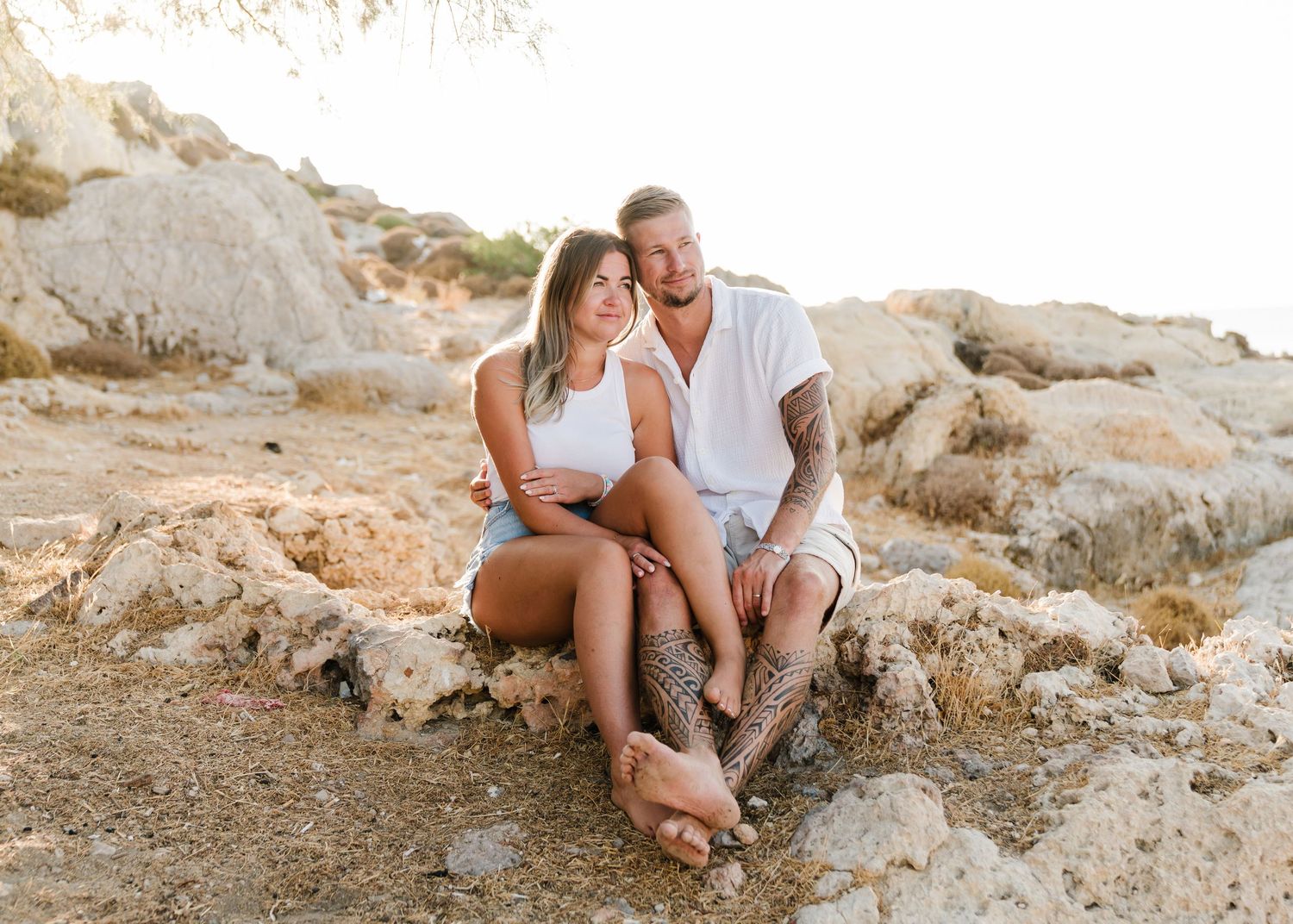 Casual couple sitting together on rocky terrain during outdoor photo session. Fotograf Rhodos