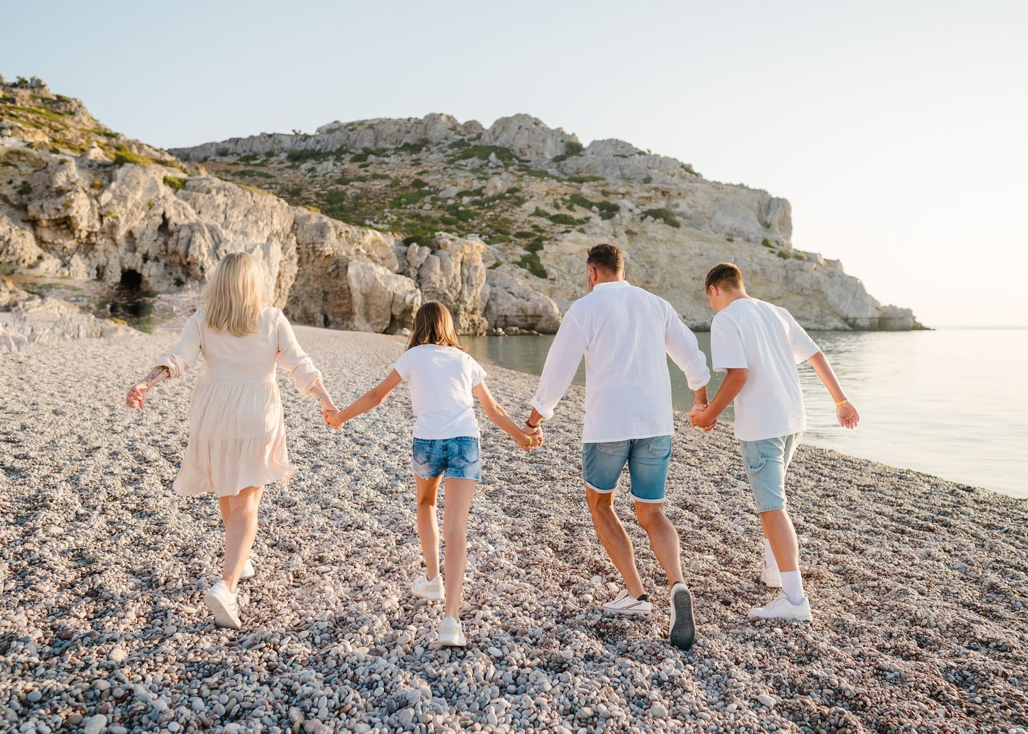 Family walking together along Mediterranean coastline with scenic mountain backdrop. Fotograf Rhodos