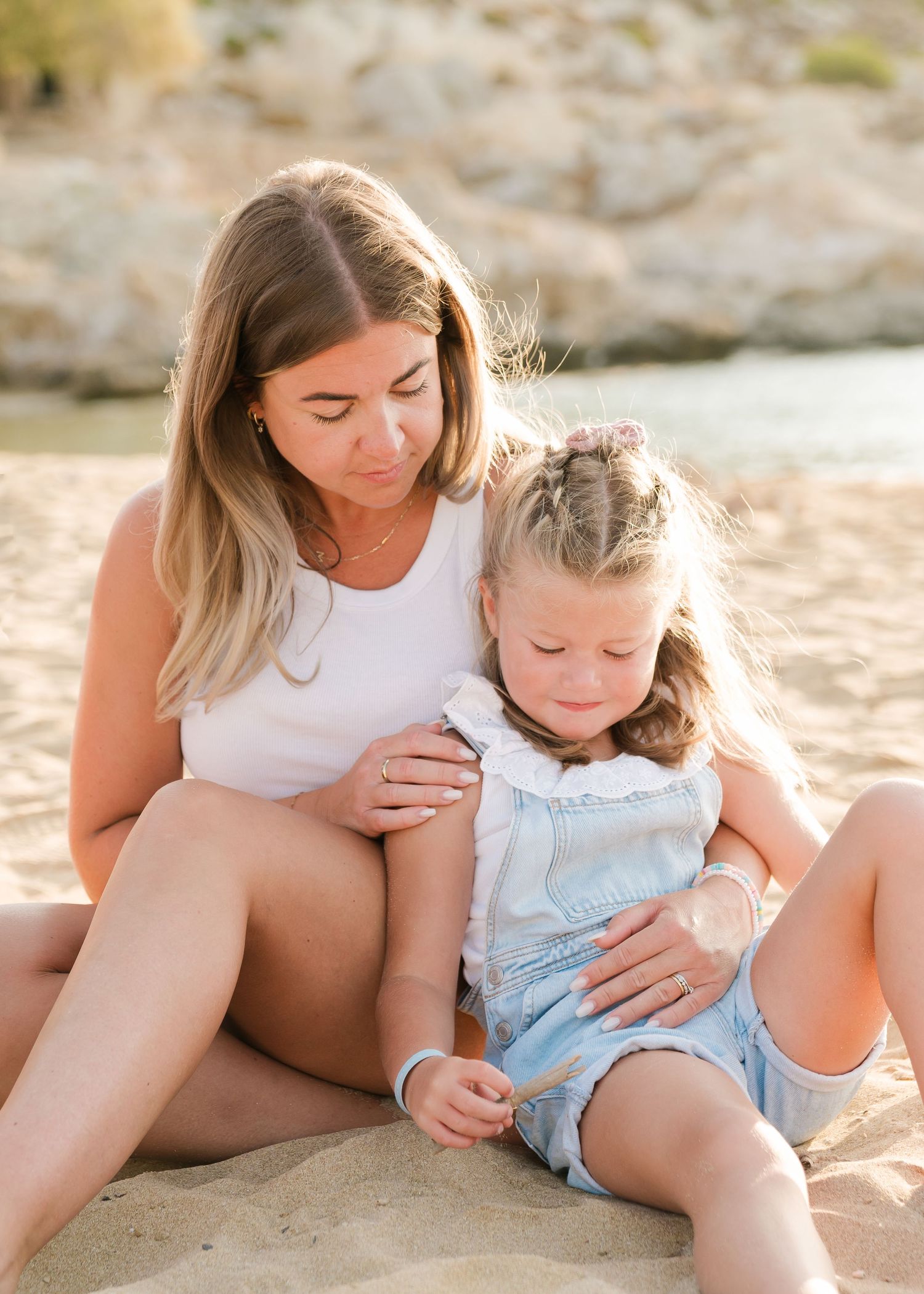 Mother and child sharing tender moments while resting on beach sand. Fotograf Rhodos