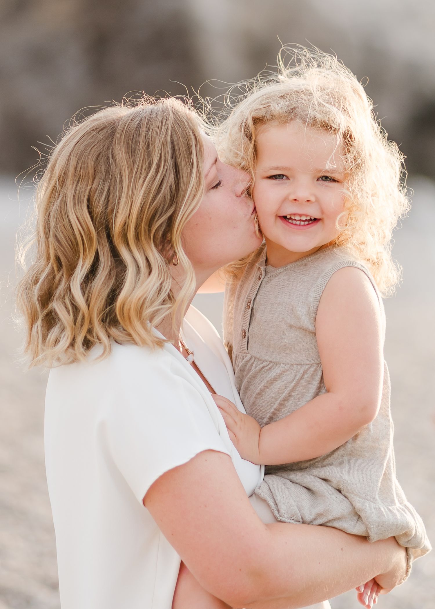Sweet moment captured between parent and child on beach with rocky backdrop. Fotograf Rhodos
