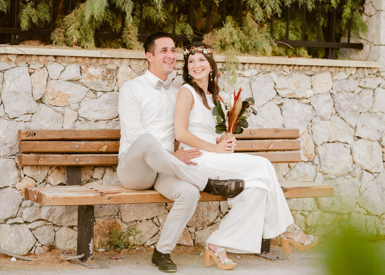 Liebespaar entspannt auf Holzbänken vor dekorativer Steinwandkulisse. Hochzeiten Griechenland - Hochzeitsfotograf Rhodos Tina Lucius