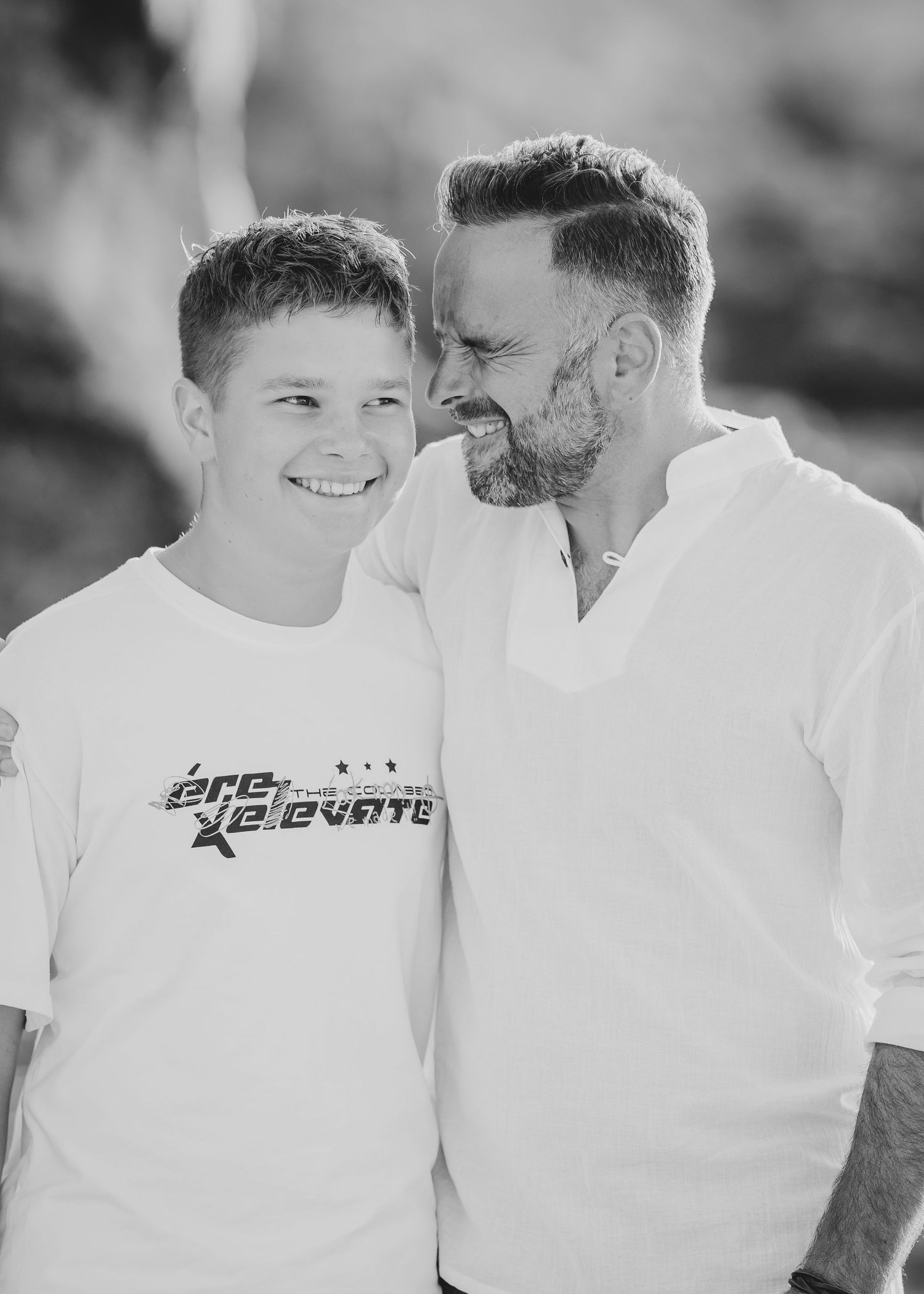 A black and white portrait shows two people sharing a candid moment against a blurred background. Fotograf Rhodos