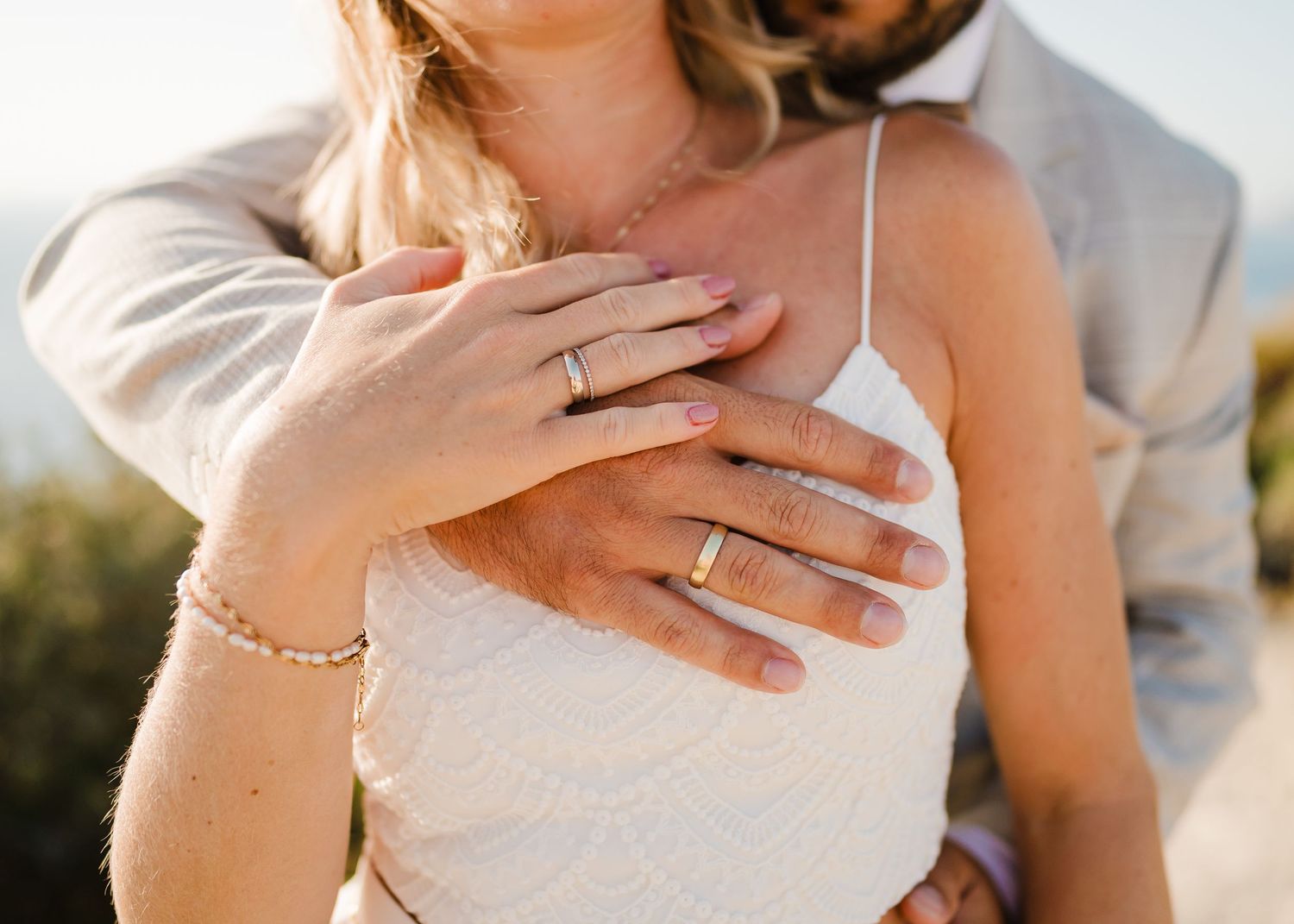 Nahaufnahme der Hände mit Eheringen und zartem Schmuck gegen weiße Hochzeitskleidung. Fotografin Rhodos - Hochzeitsfotograf Rhodos Tina Luci