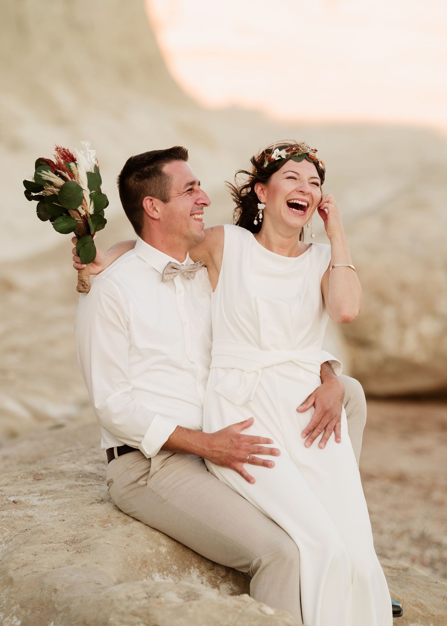 Offene Momente des Lachens und der Freude, eingefangen zwischen einem Paar auf felsigem Küstengelände. Hochzeiten Griechenland - Hochzeitsfo