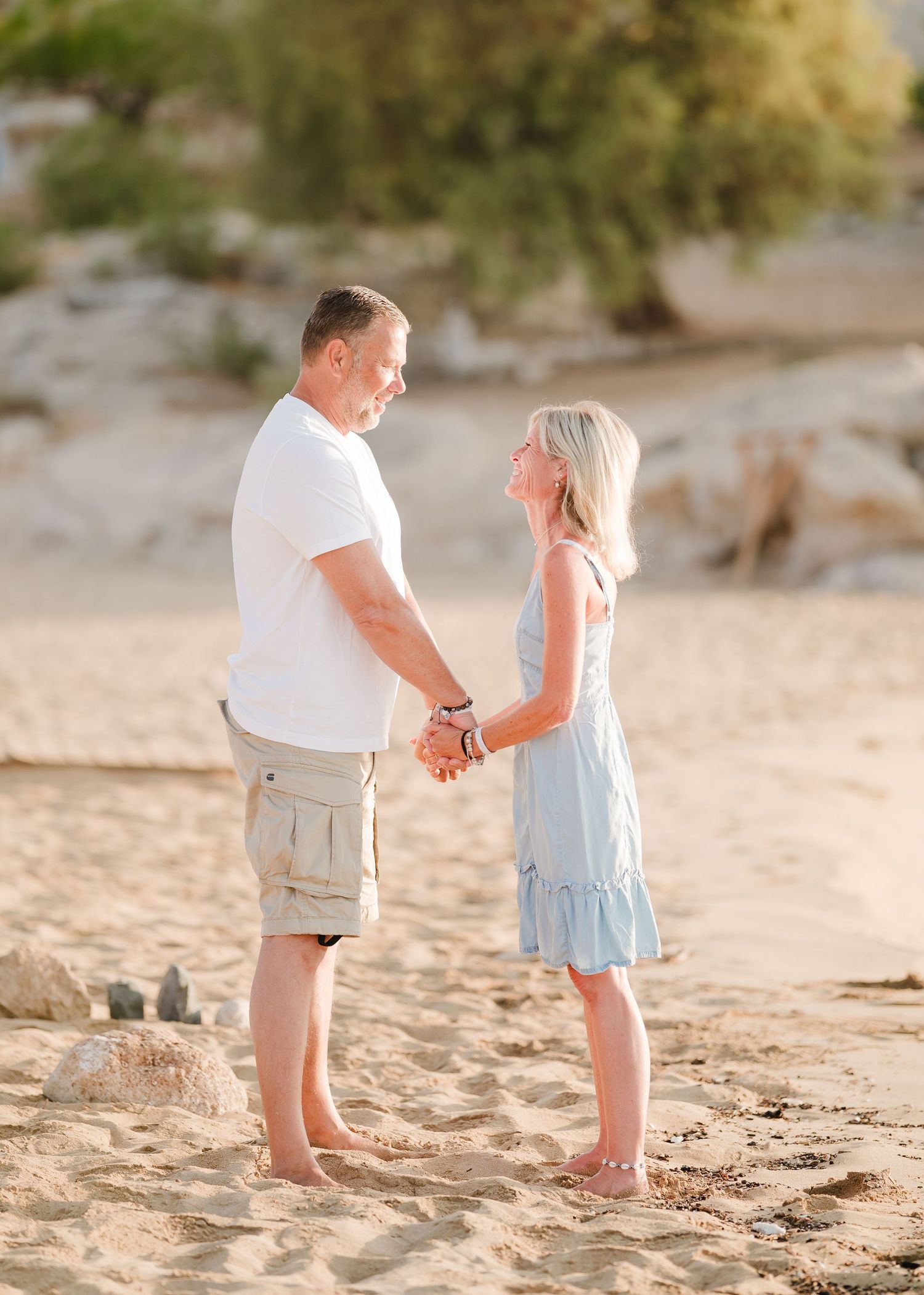 Couple holding hands while standing together on sandy beach at sunset. Fotograf Rhodos